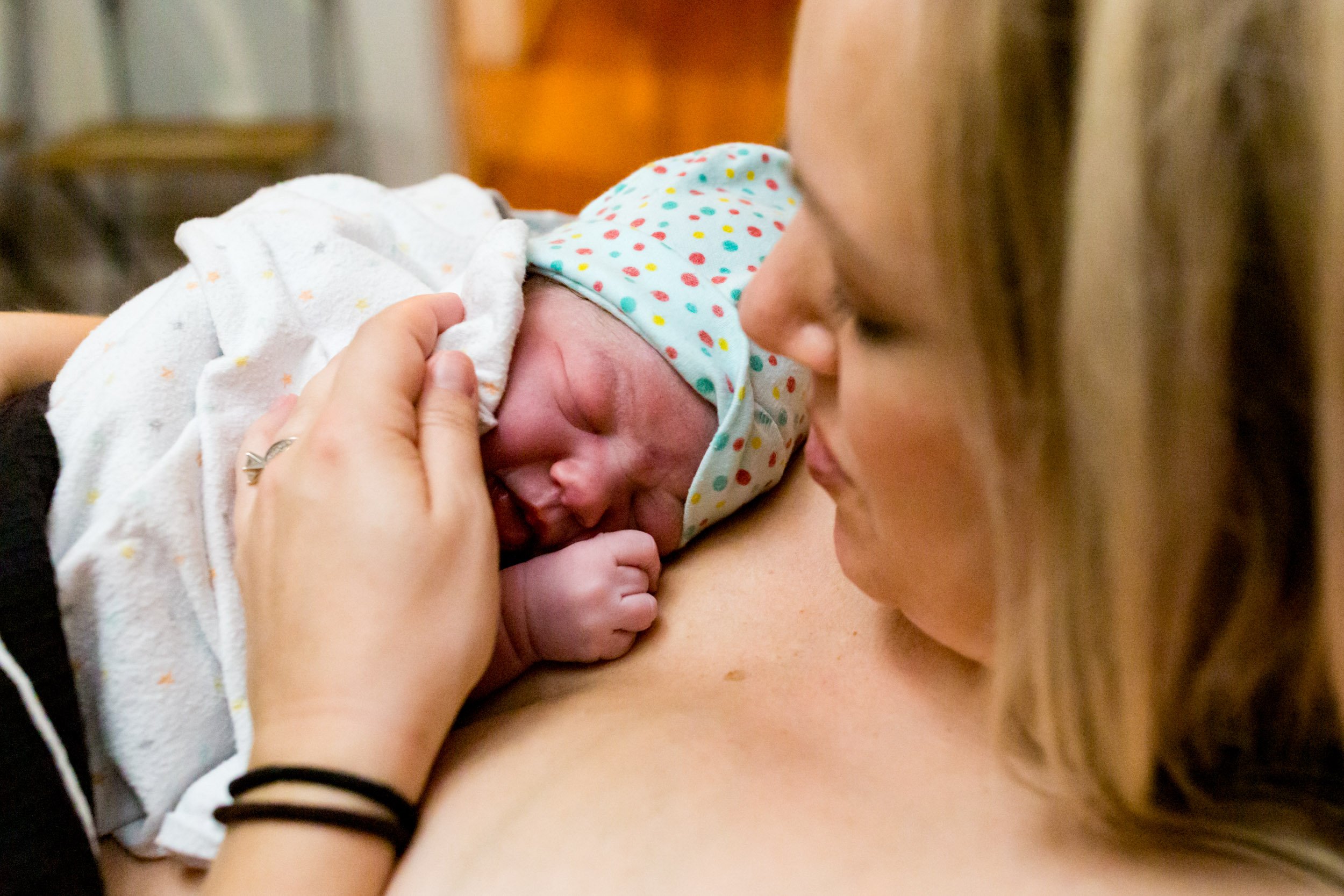 mom holding her newborn baby girl on her chest just after birth