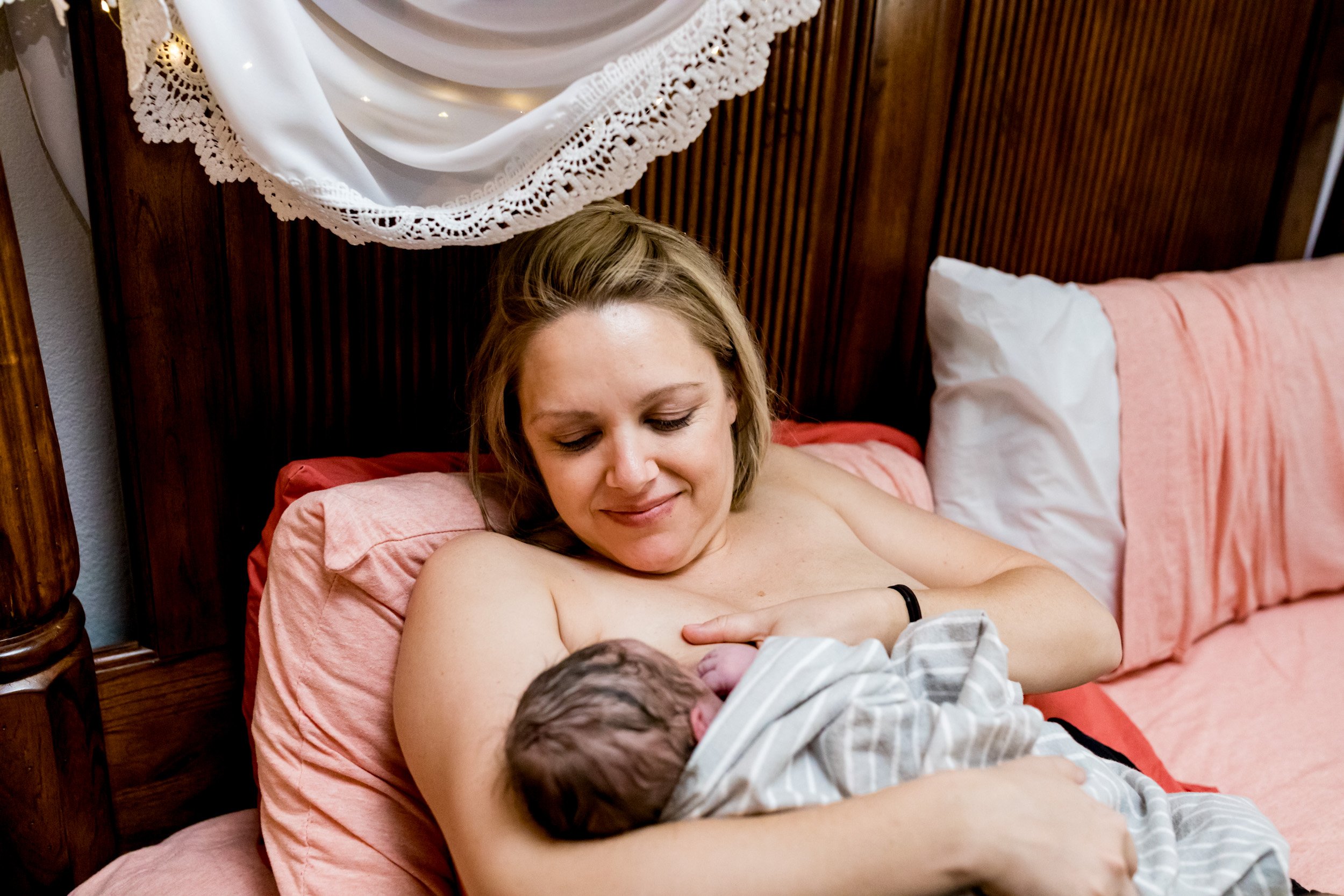 birth mom smiling sweetly as she nurses her baby girl