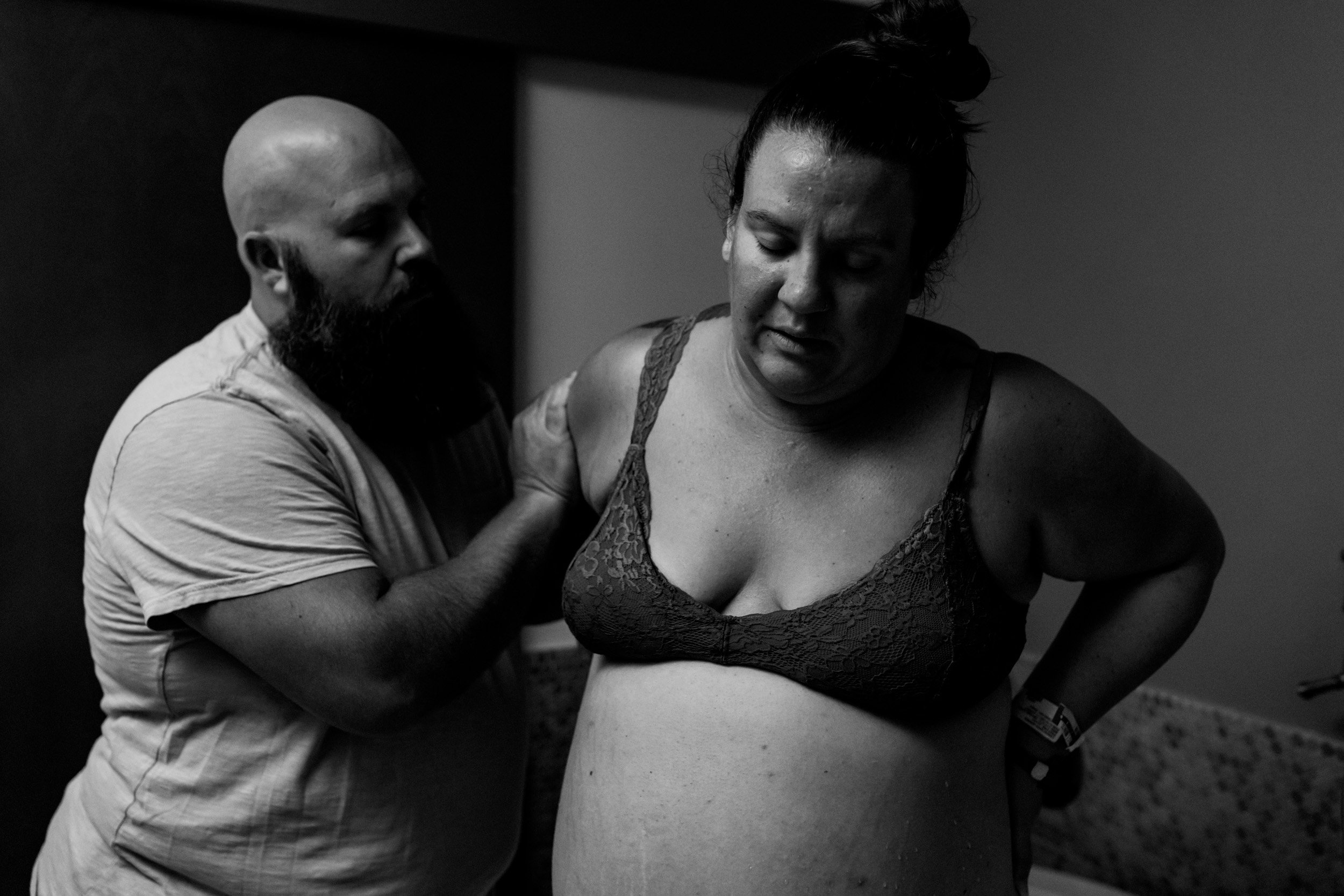 husband supporting pregnant wife as she gets out of the birth tub