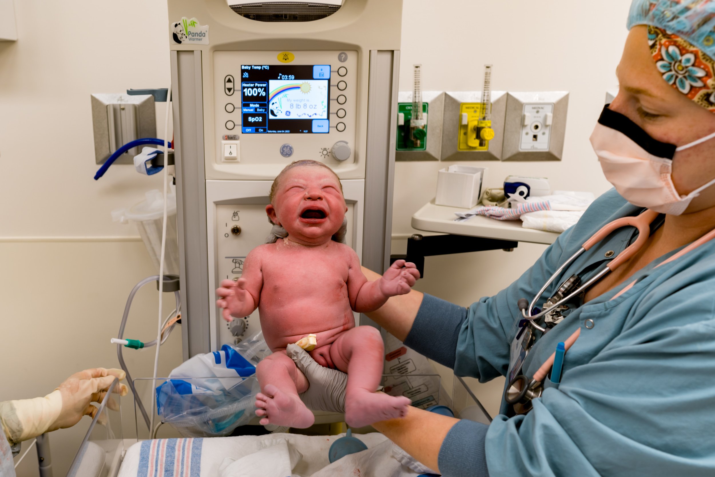 newborn baby being held up by nurse