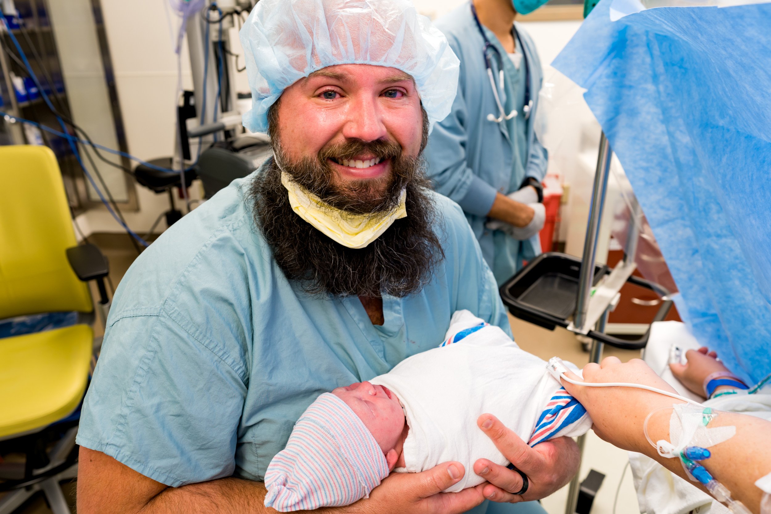 birth dad smiling as he holds his newborn baby girl
