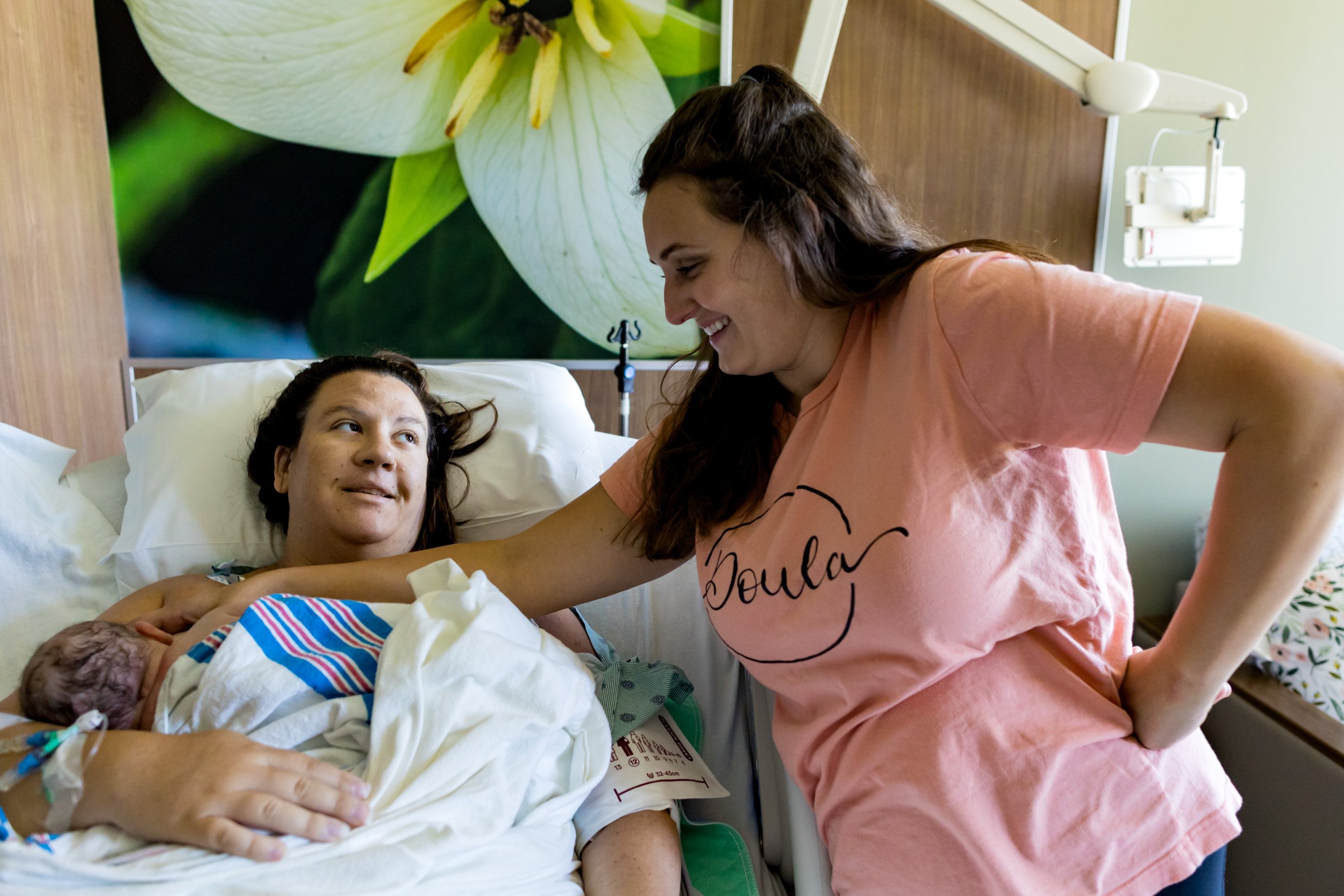 birth mom smiling at doula while holding her baby