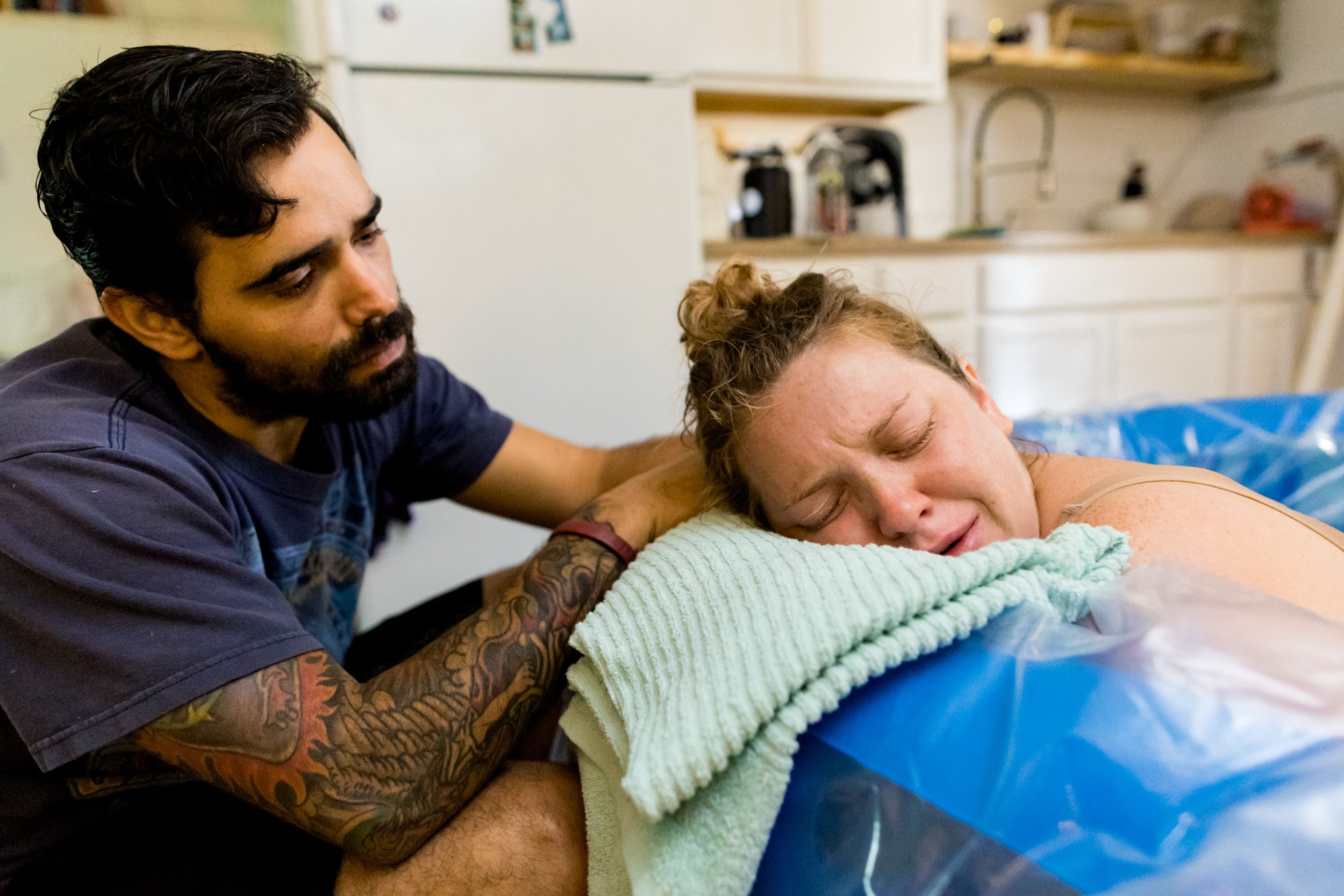 husband comforting his wife as she labors in the birth pool