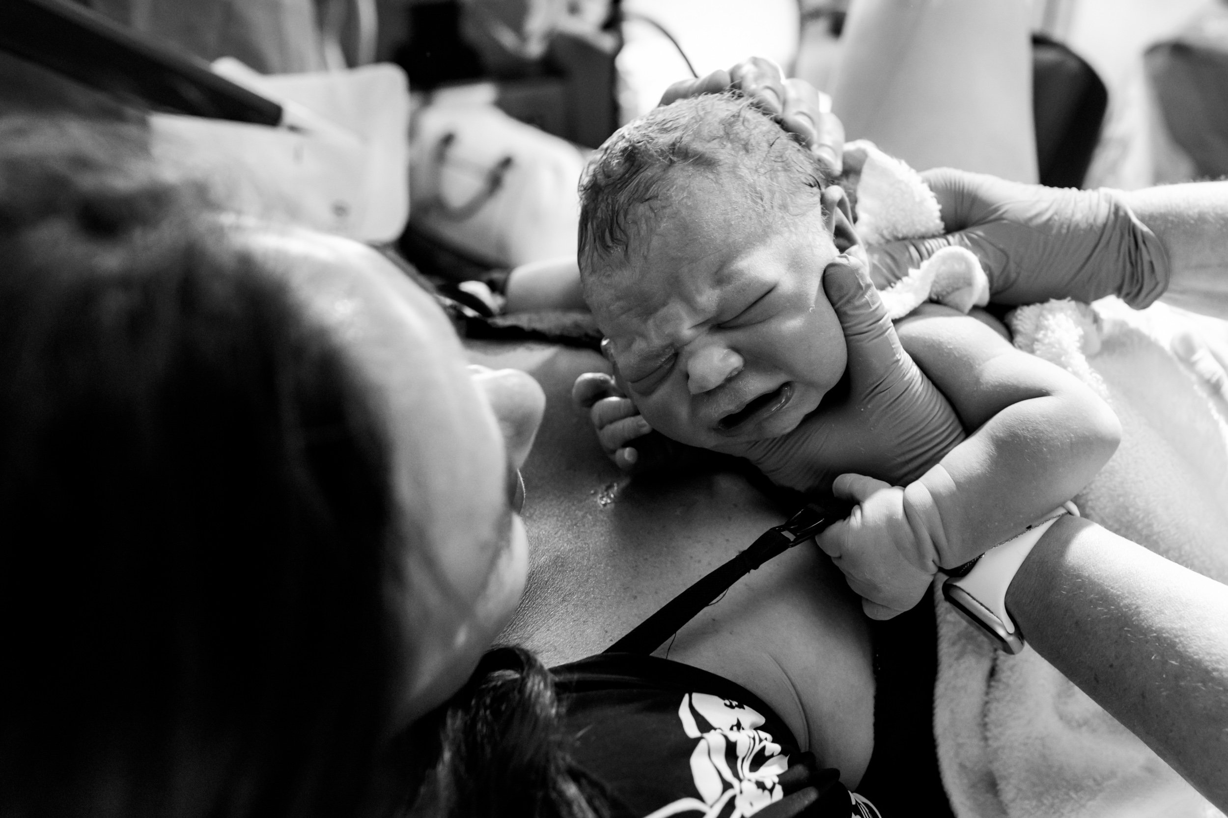 newborn baby being placed on his mother's chest for skin-to-skin