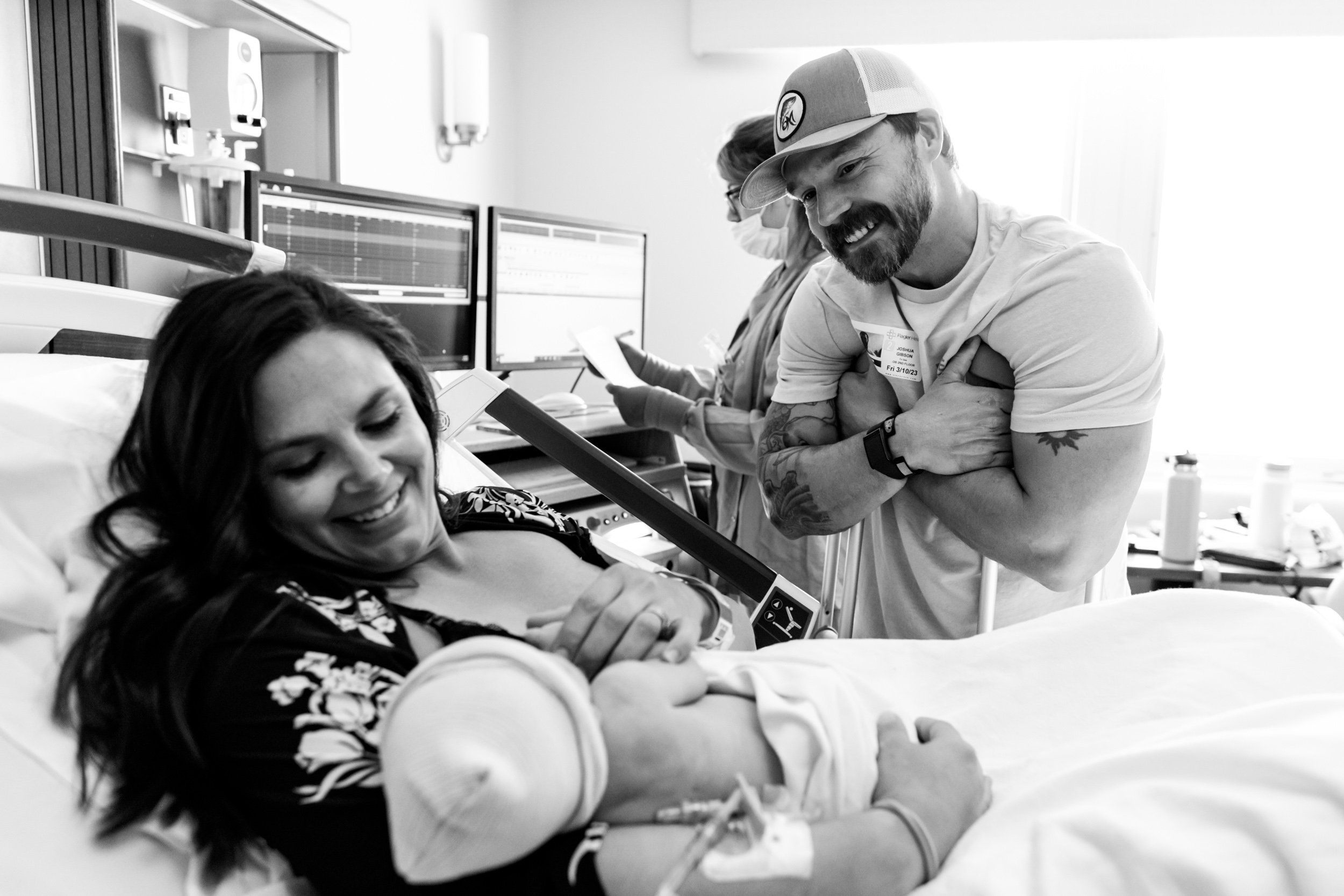 dad looking at wife and their baby boy just after birth