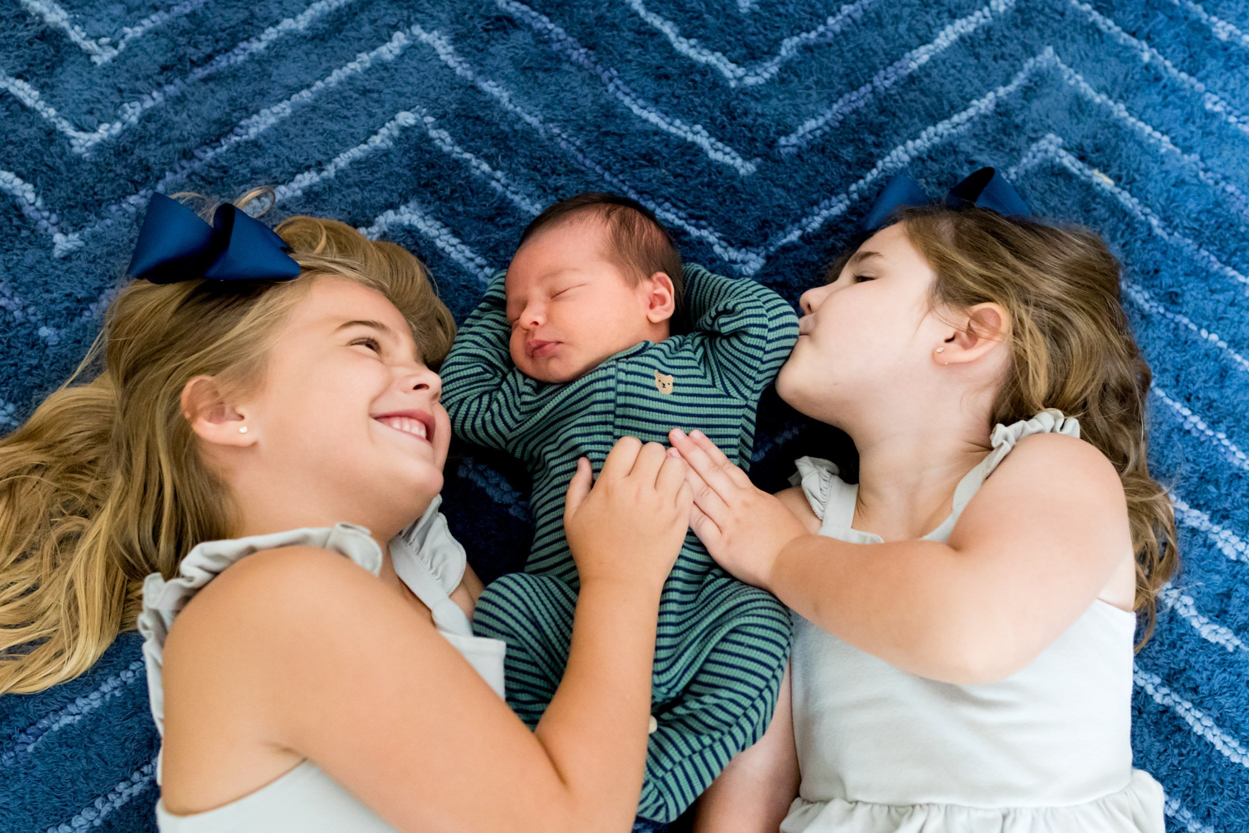 two girls snuggling with their baby brother