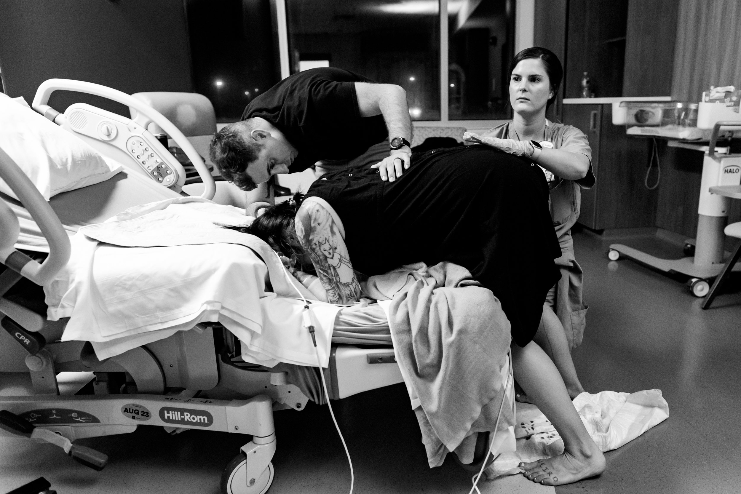 nurse monitoring baby's heart rate while laboring mom is comforted by husband