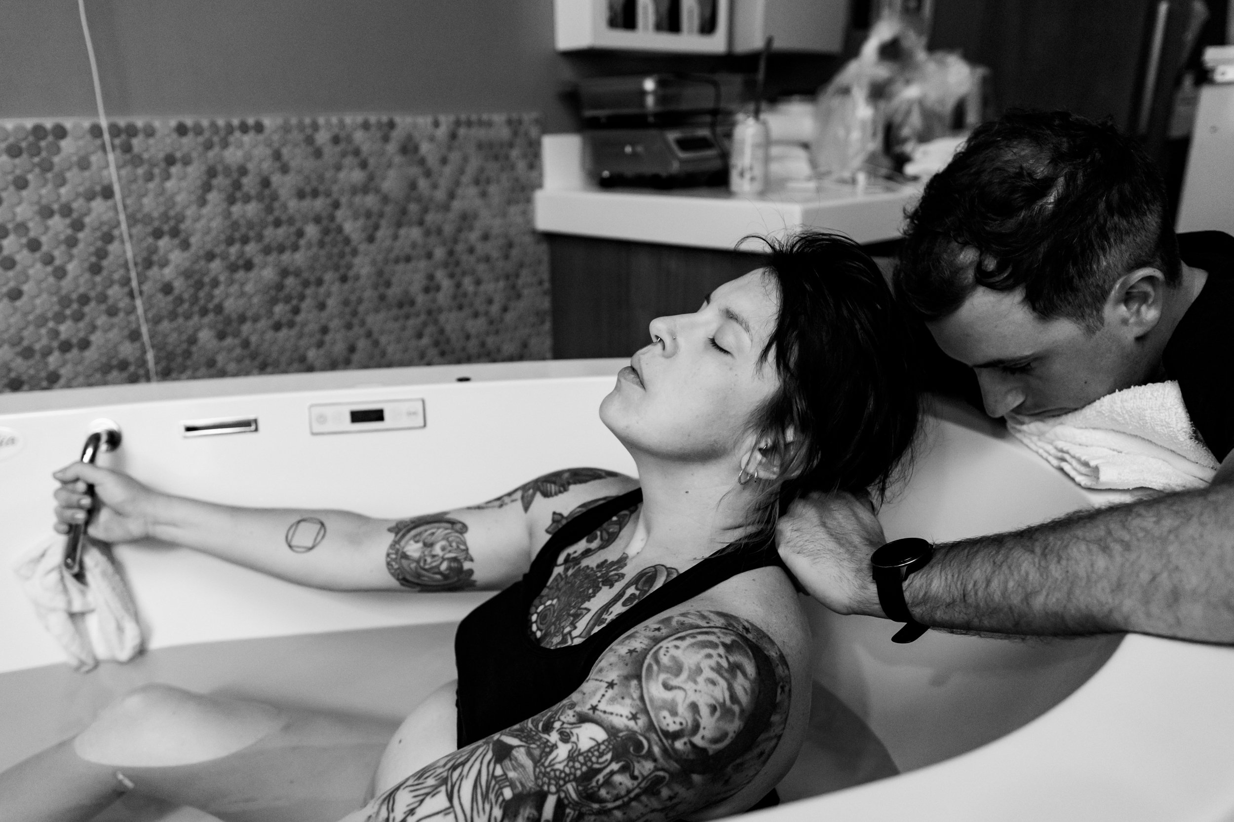 husband comforting his laboring wife in the birth tub