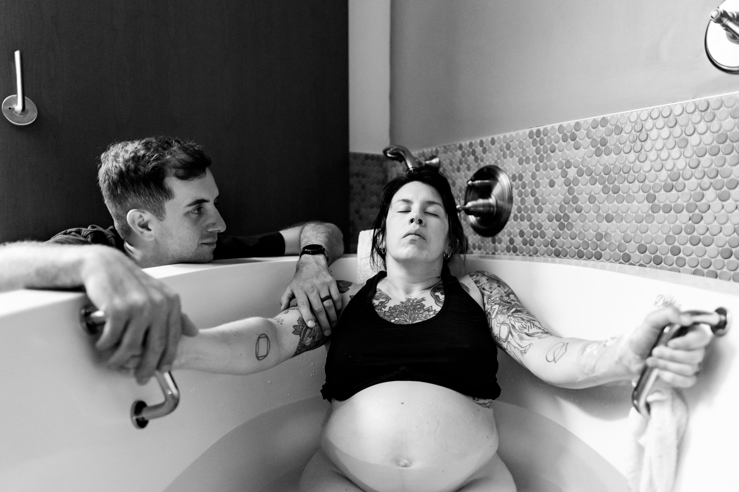 laboring mom holding onto tub handle while her husband looks on