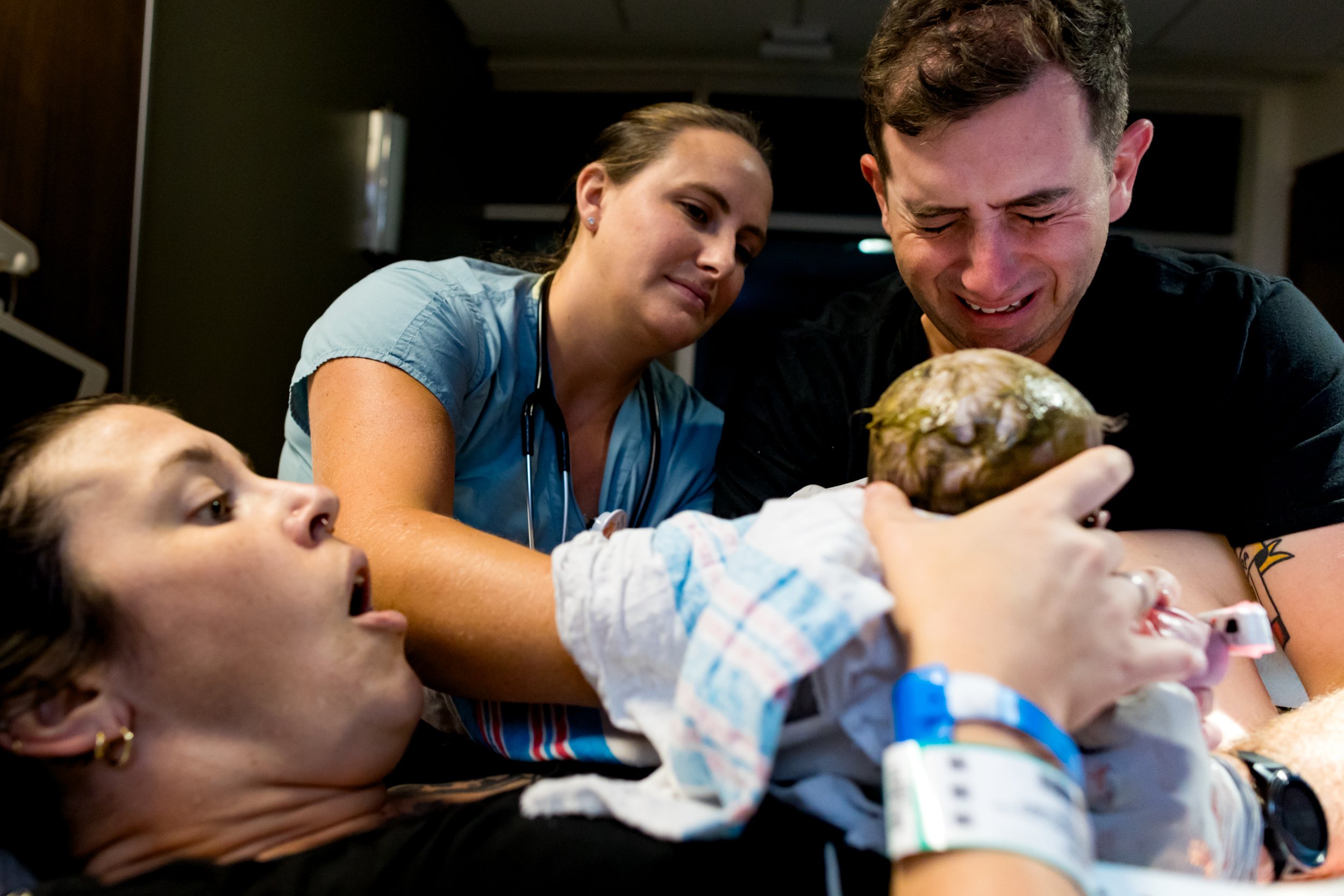 mom holding newborn baby just after birth, and dad crying