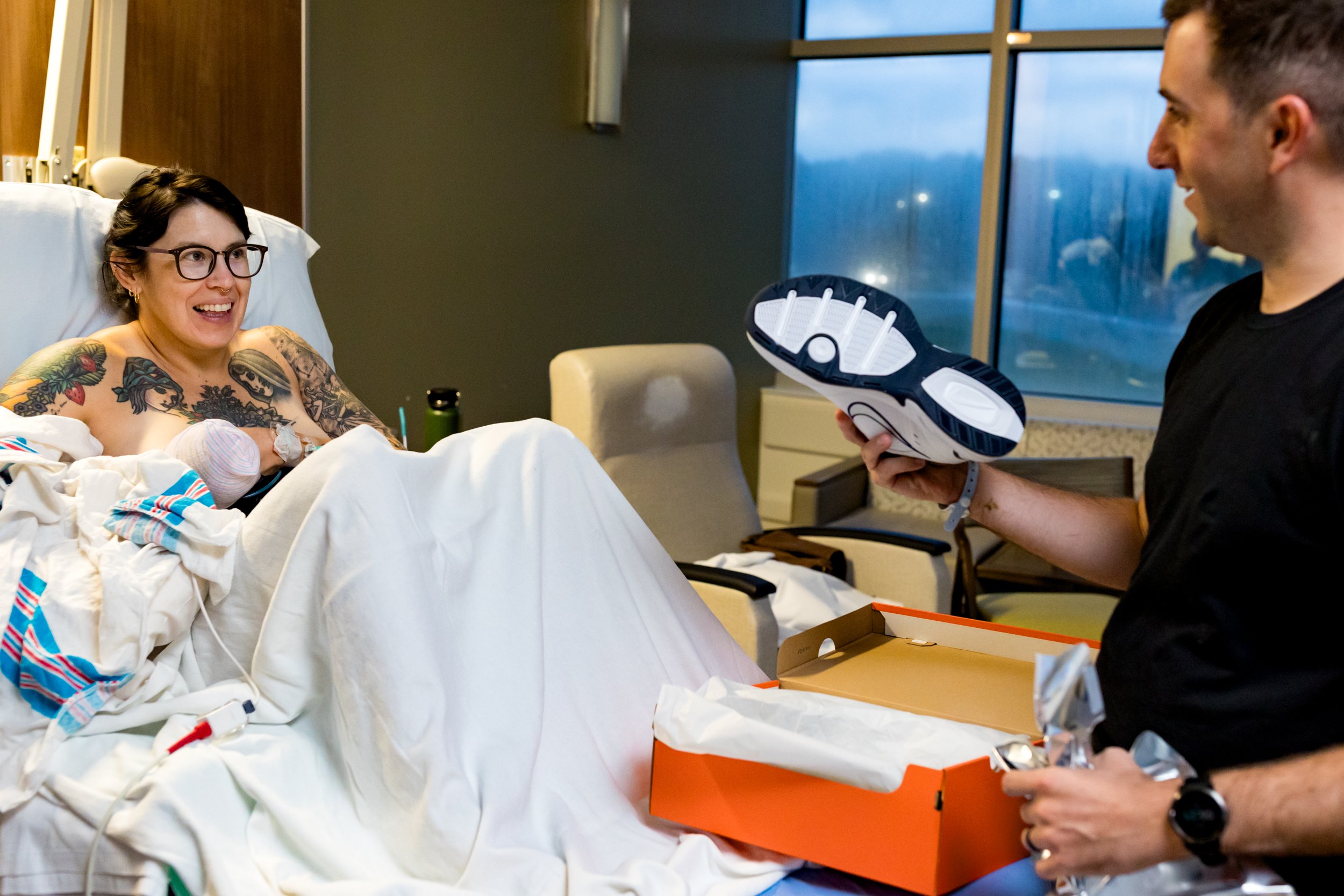 husband laughing after wife gets him "dad shoes" after the birth of their baby