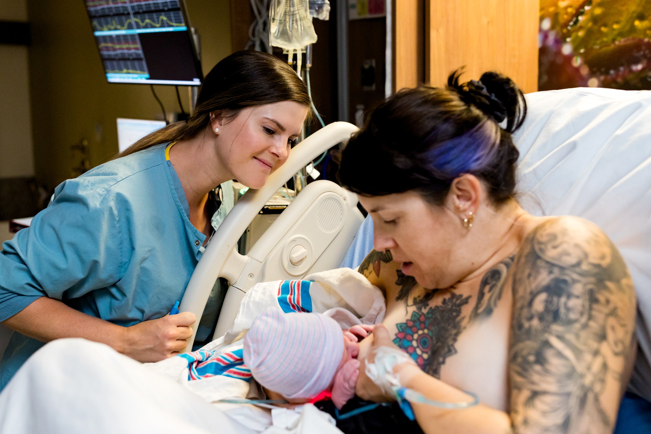 nurse looking on as baby latches for the first time
