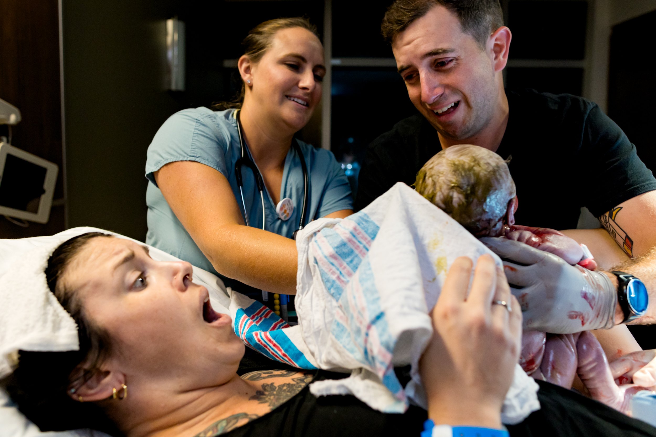 dad crying as mom reaches out for her baby just after birth