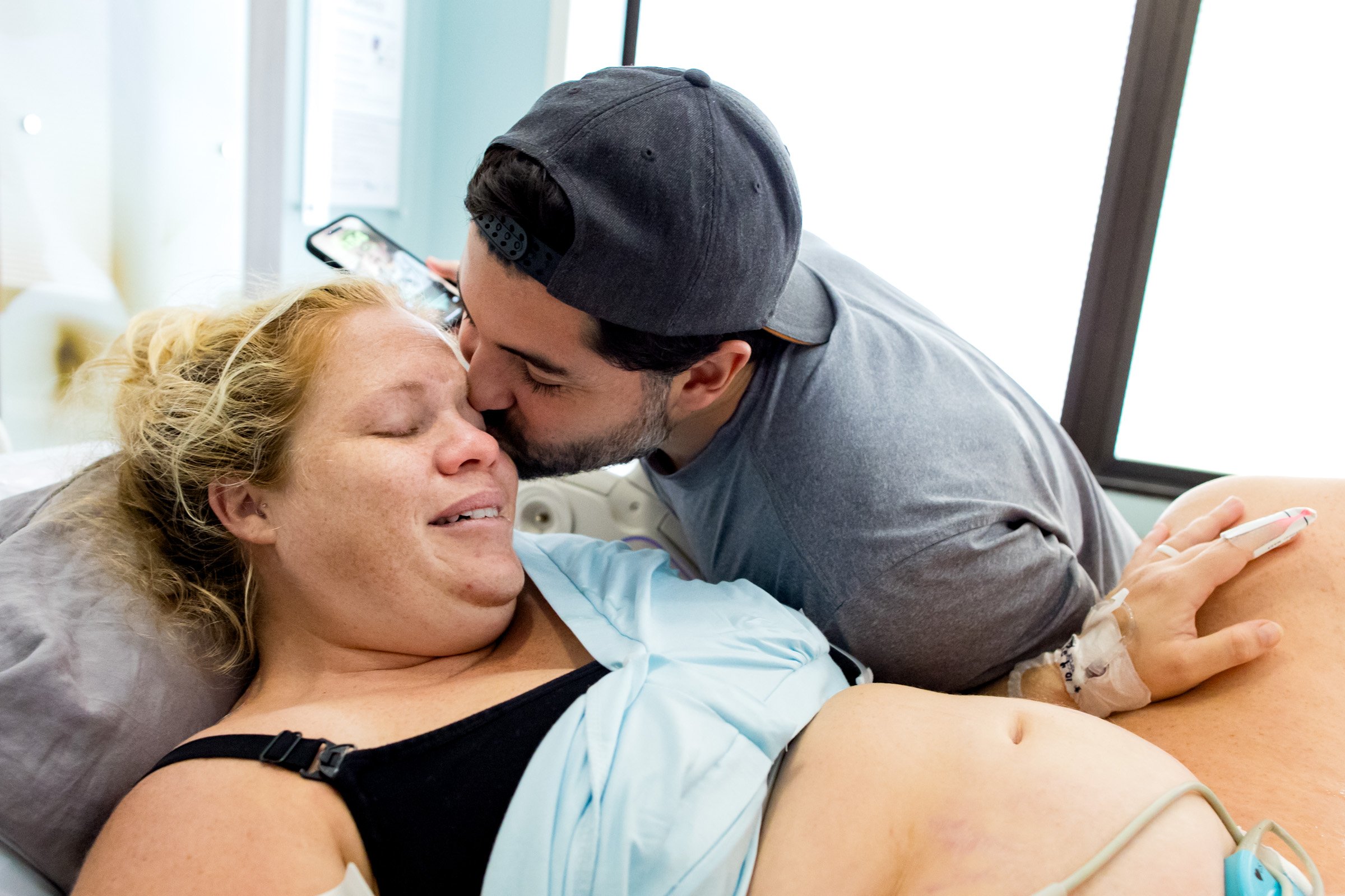 husband kisses wife just after the birth of their child