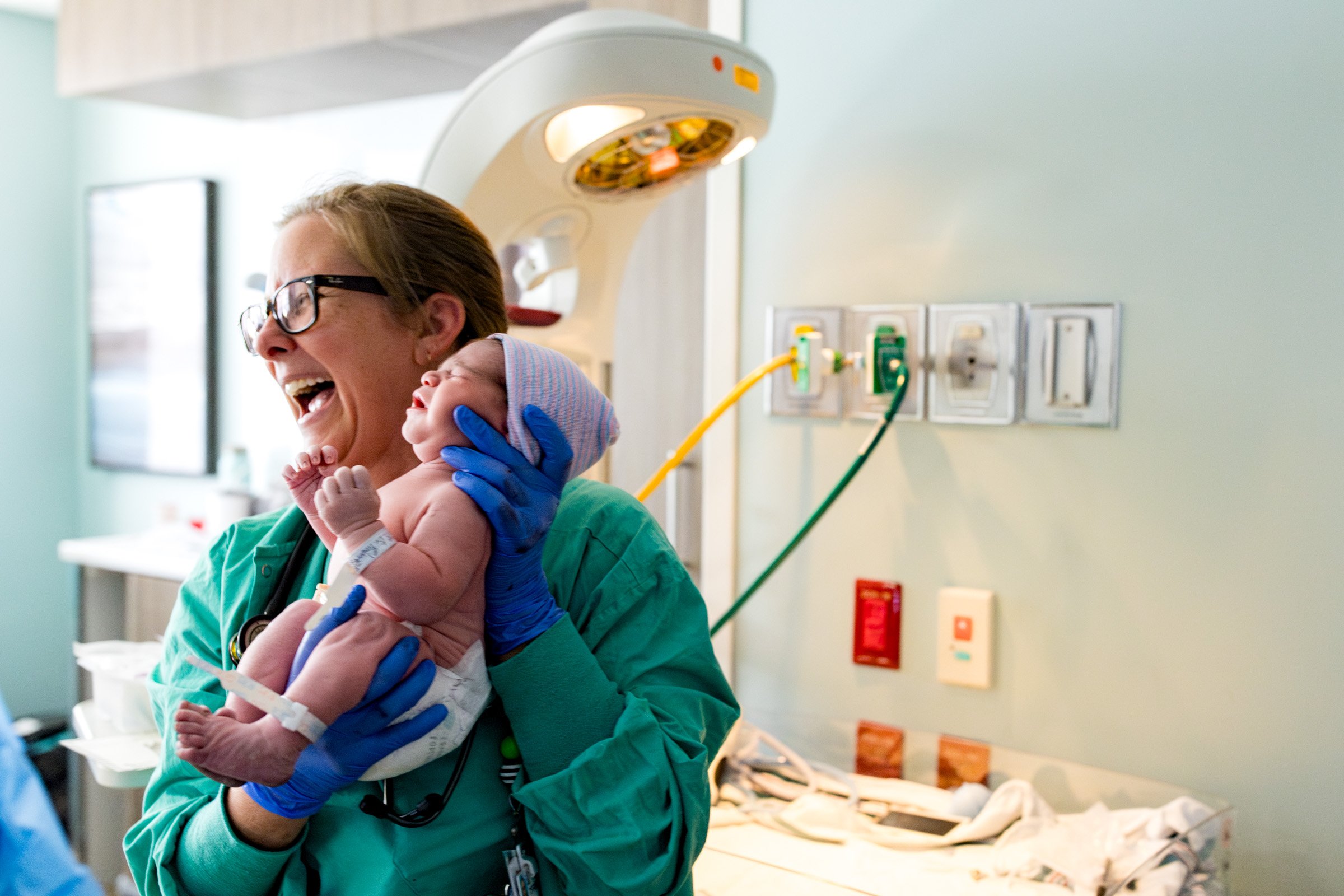 nurse holding a baby and smiling