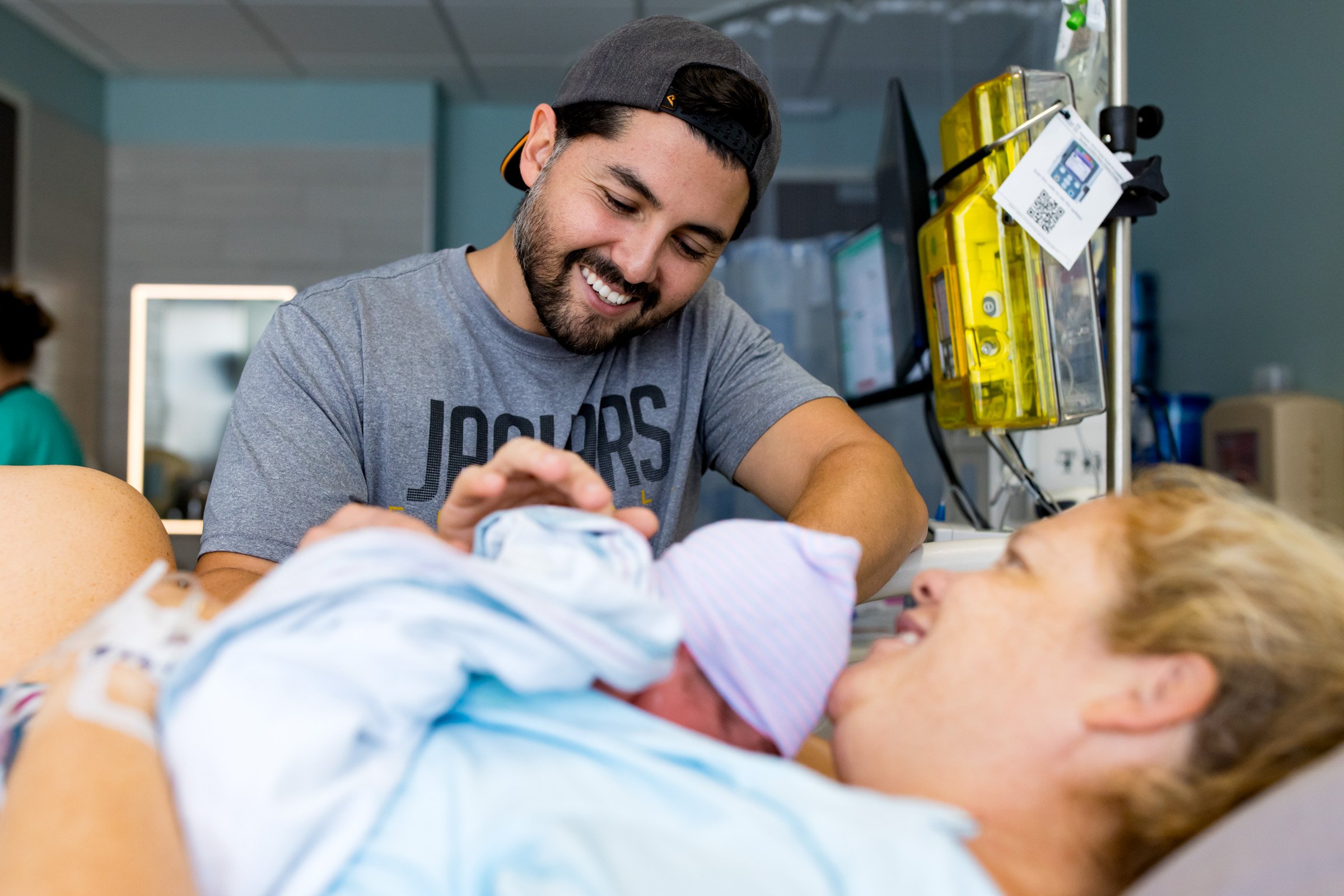 dad smiling at his wife and newborn baby