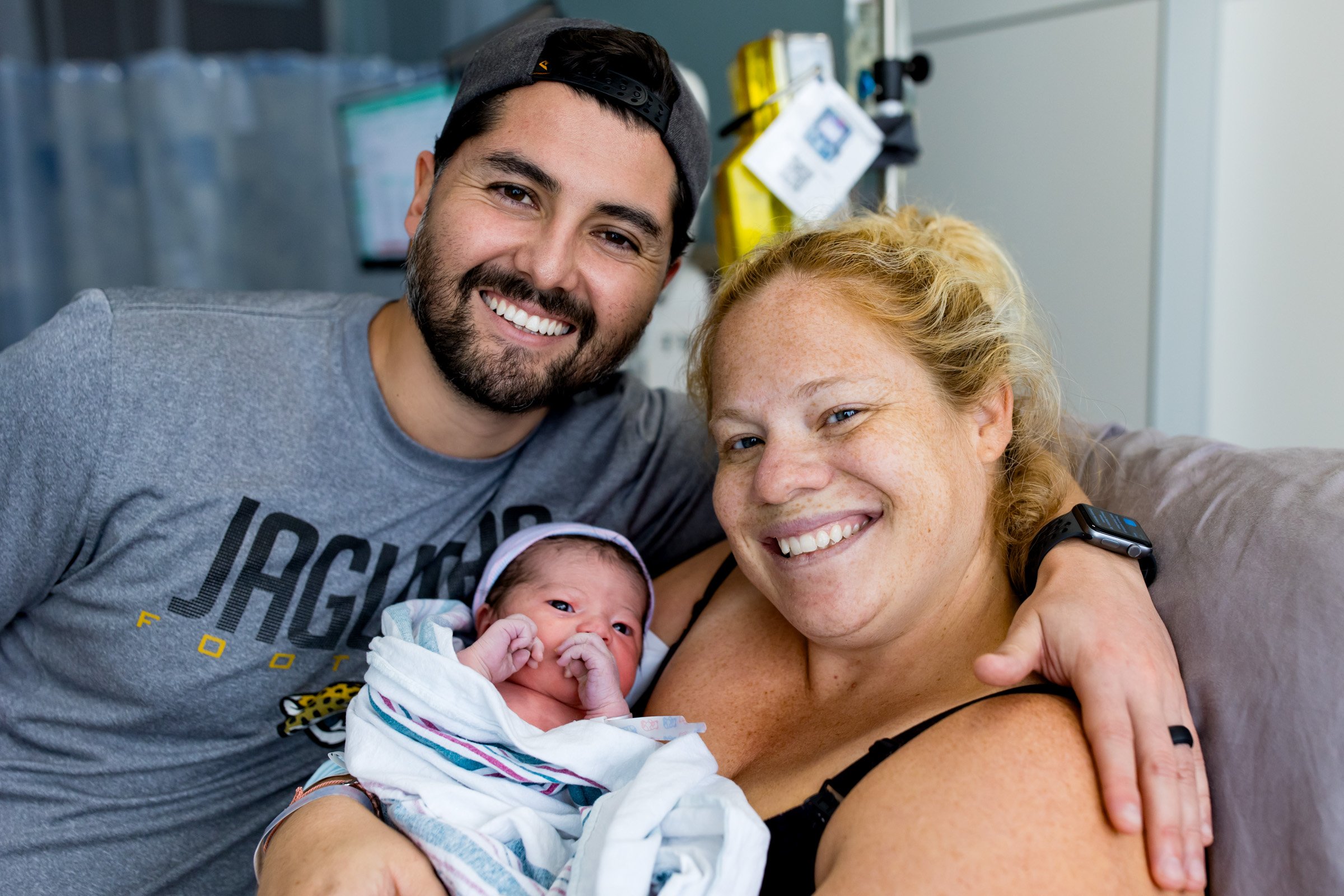 new parents smiling as they hold their newborn baby girl