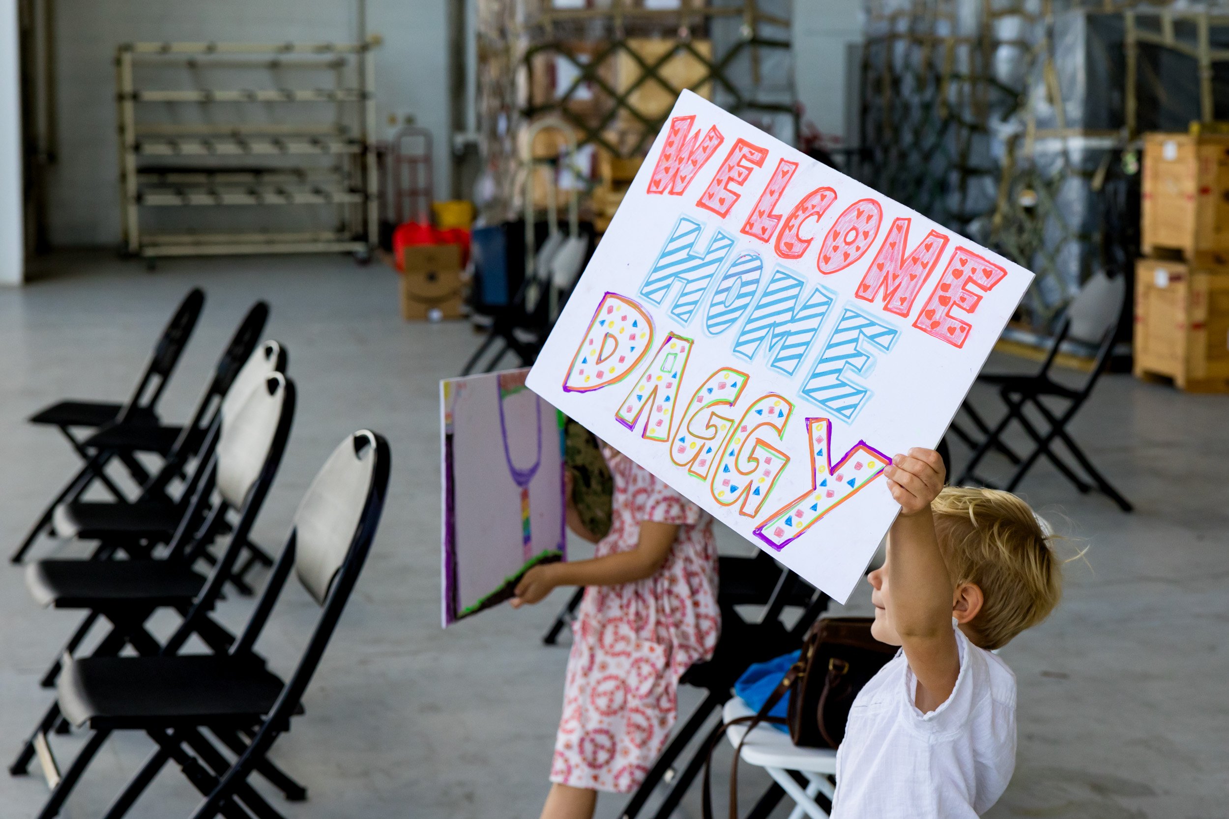 child holding up "welcome home" sign at military homecoming