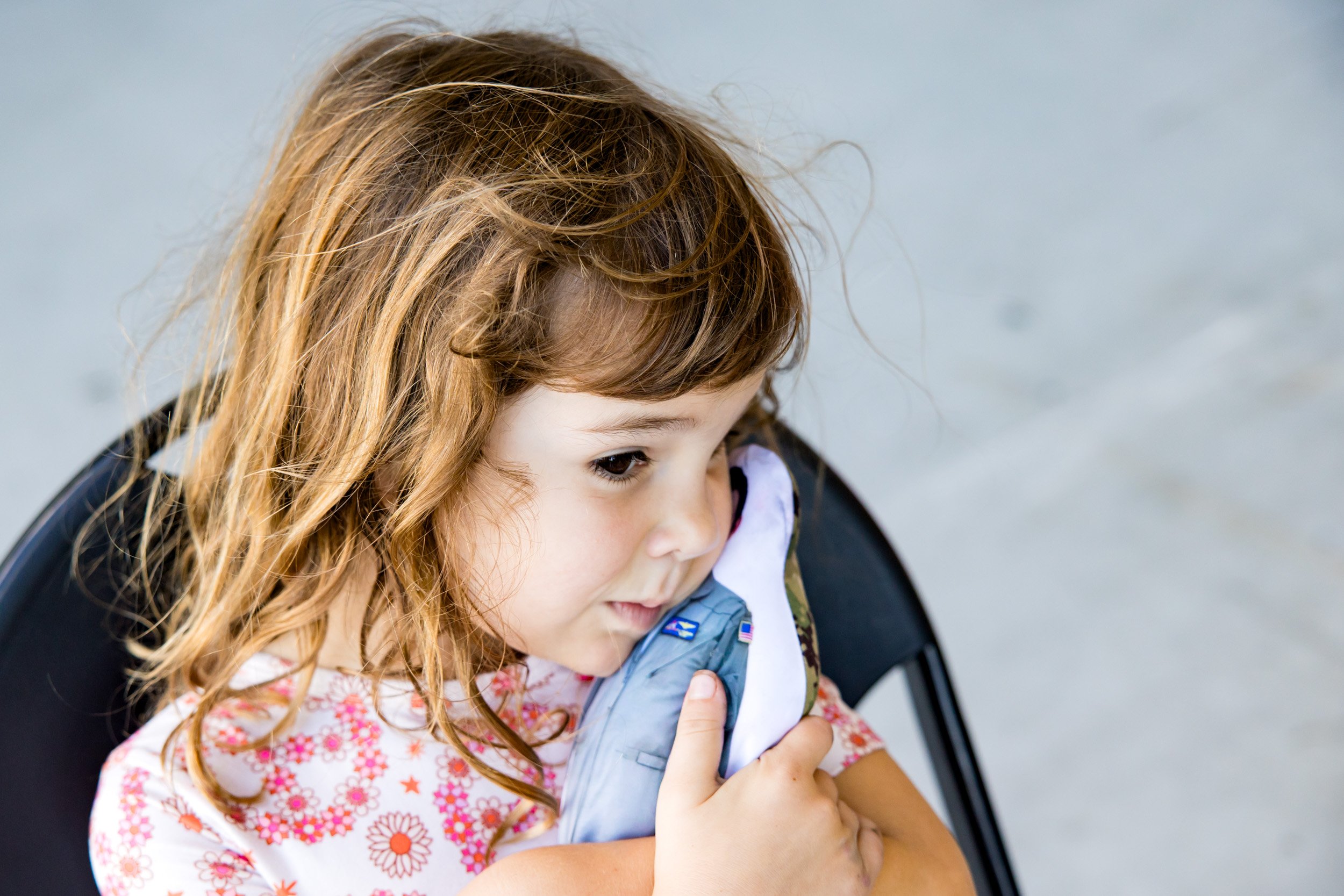 little girl hugging the pillow picturing her Navy pilot dad as she waits for him to arrive after deployment
