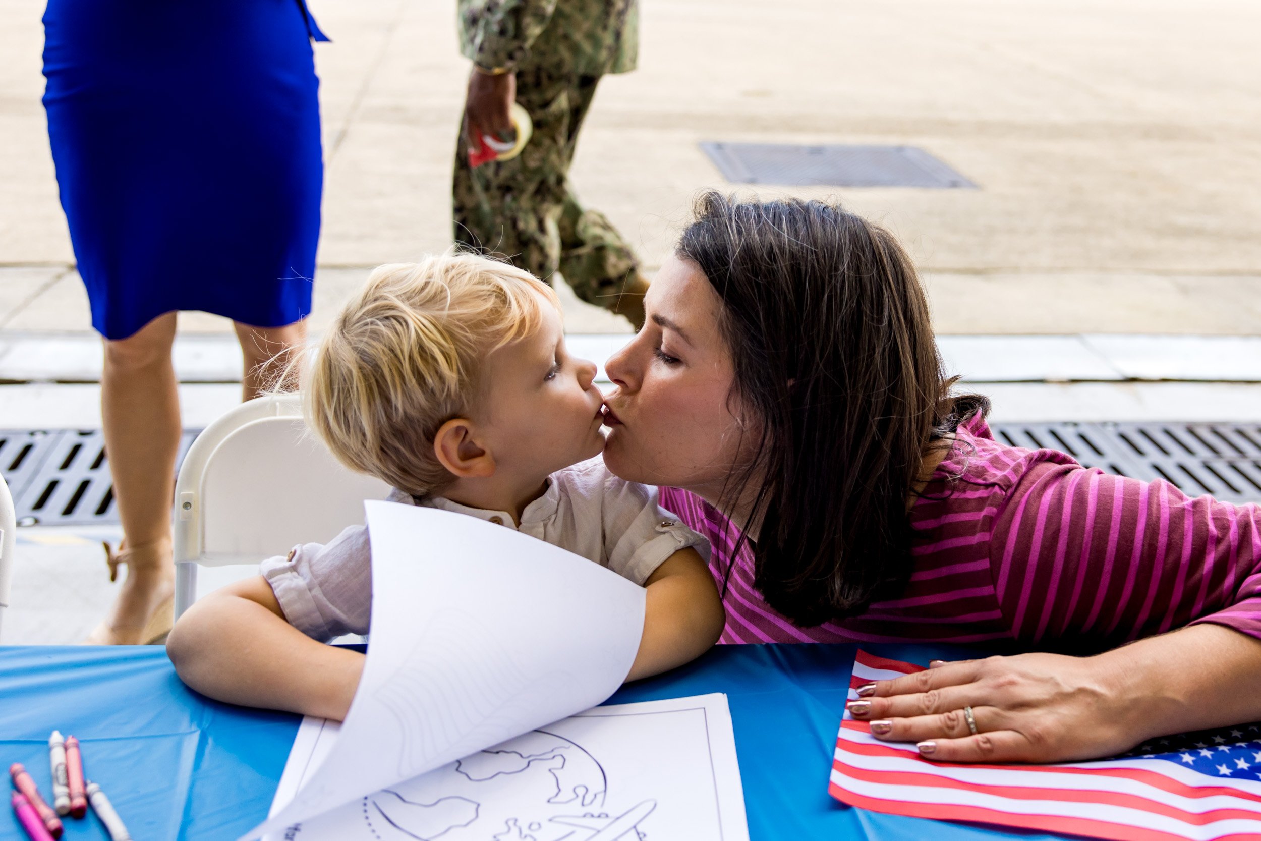 mom and little boy kissing as they wait for his dad to arrive - military homecoming