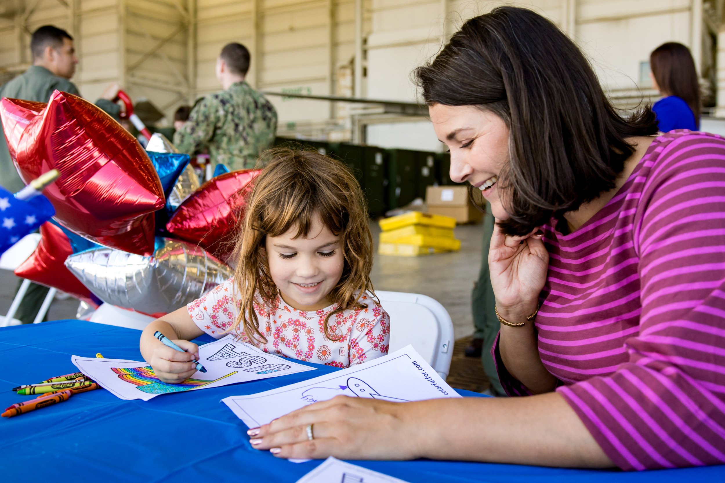 mom and daughter coloring an American flag drawing while waiting for dad's arrival