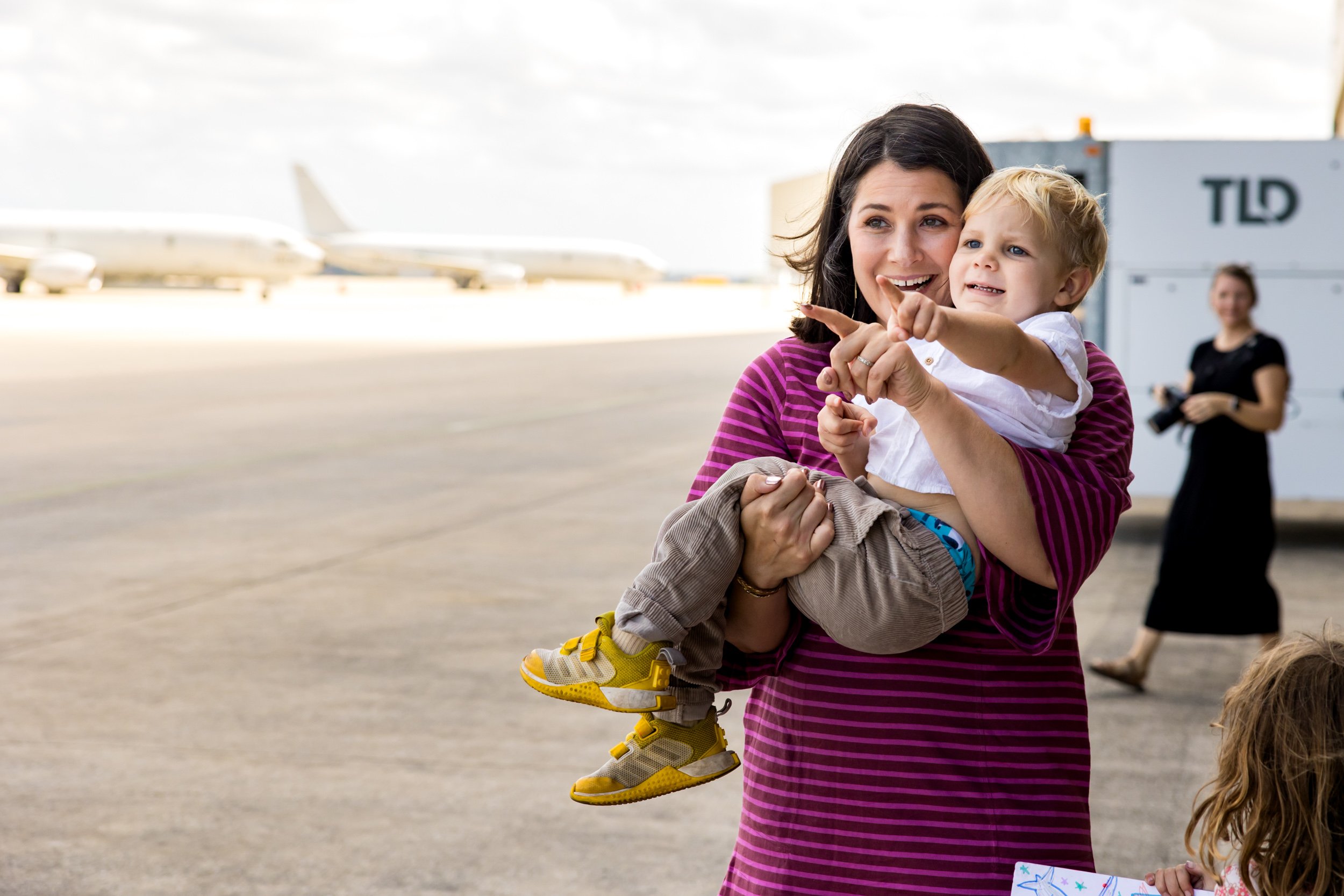 little boy pointing toward airplane flying in for military homecoming