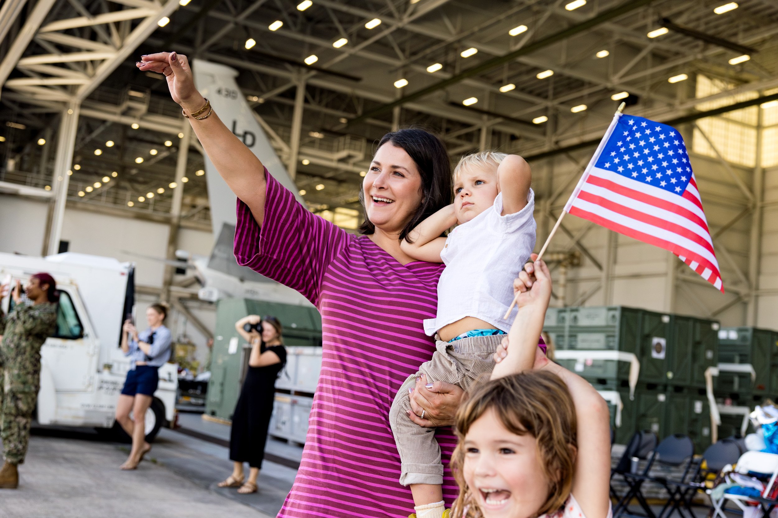family waving at airplane that just flew in for military homecoming