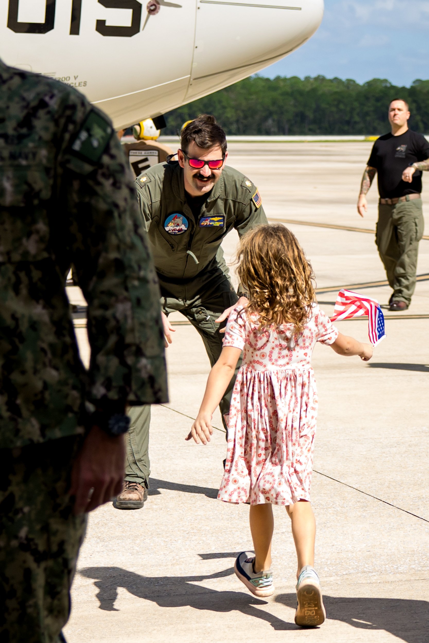 pilot dad getting ready to embrace his little girl as she runs toward him
