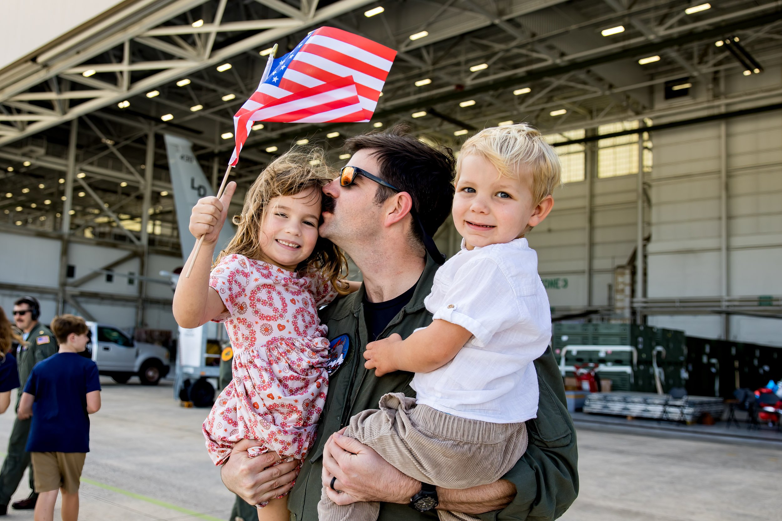 little girl holding an American flag while her dad holds her and her brother