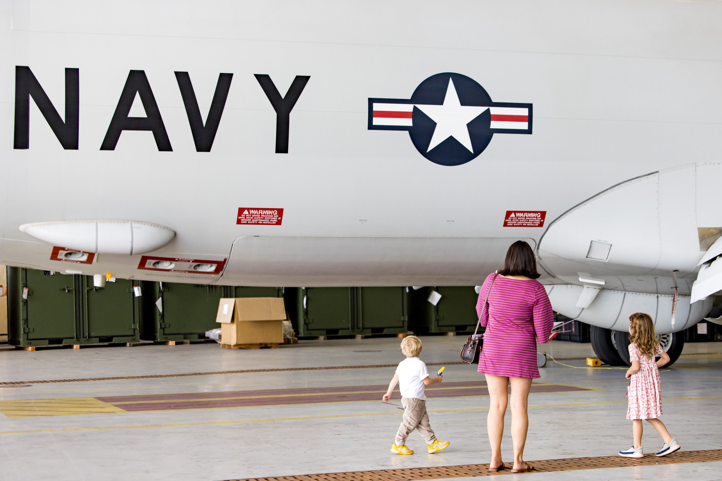 military wife and two children looking at Navy plane in hangar