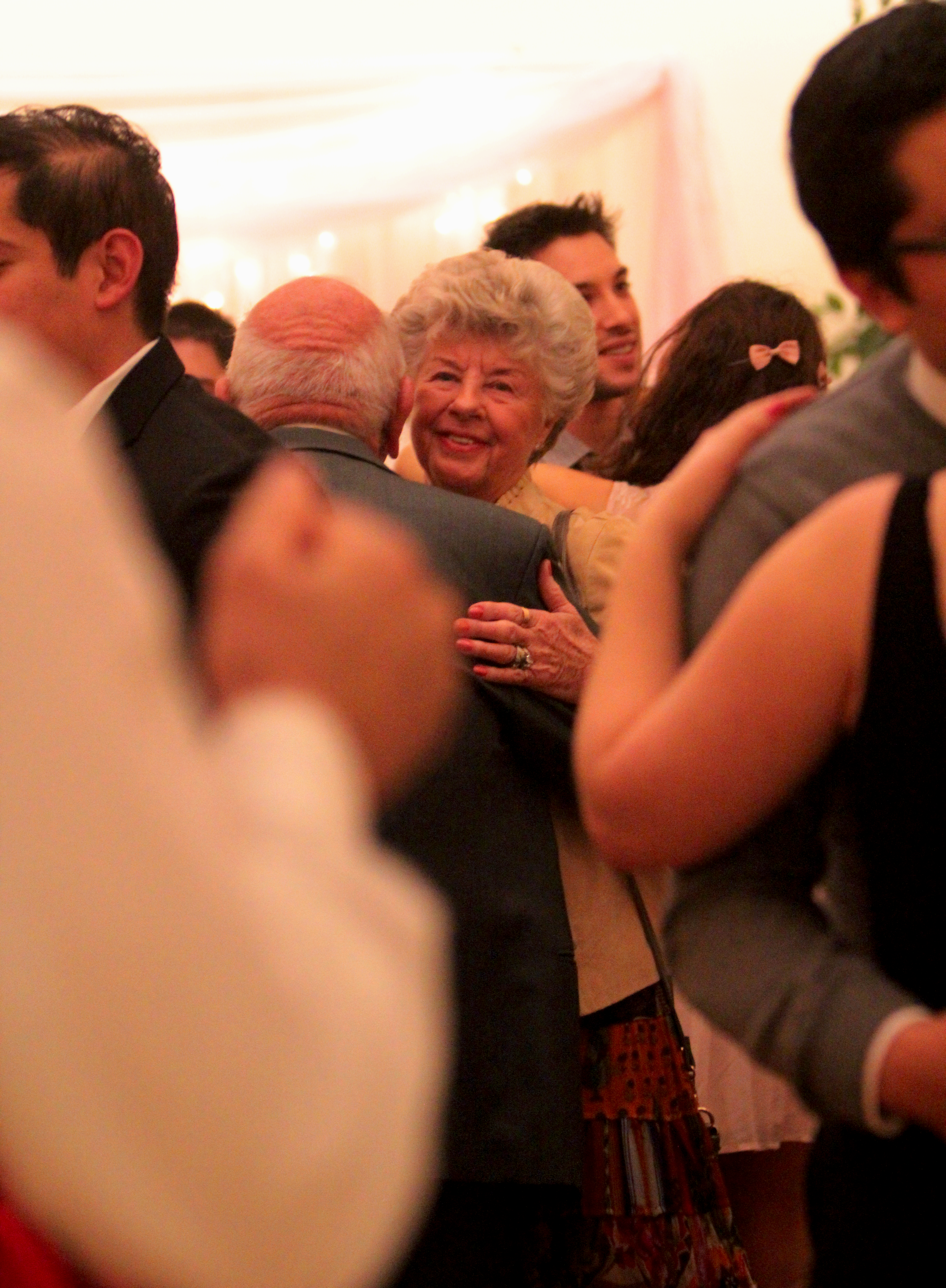 Woman smiling while dancing with her husband at reception.