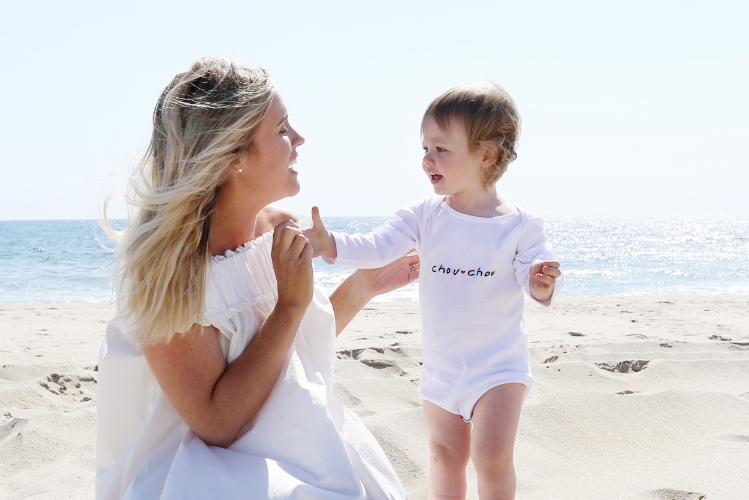 Iris wears a HATCH x Indego Africa onesie on the shore. 