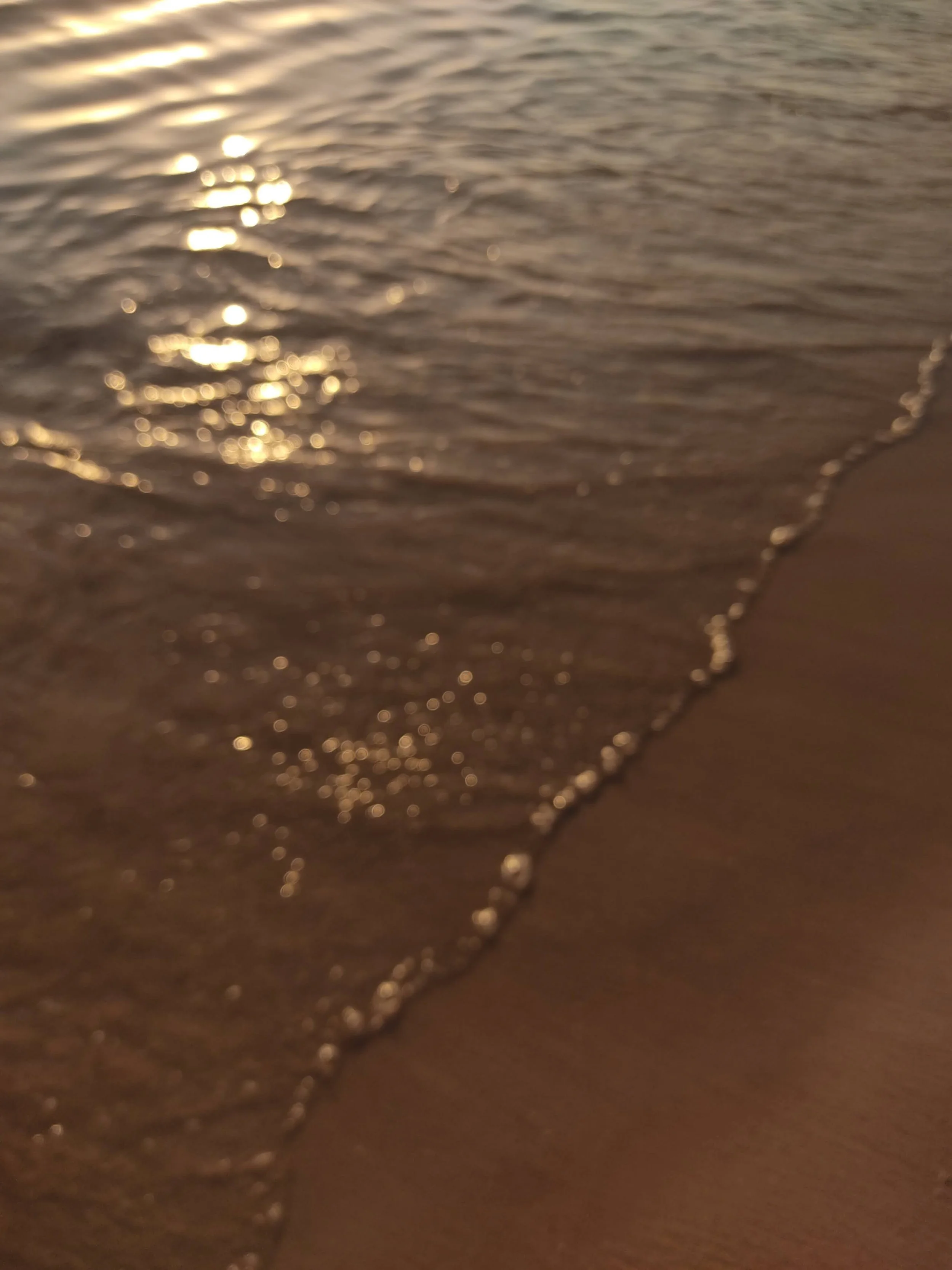 Soft waves coming to the shore, reflecting the delicate light of the sunset.