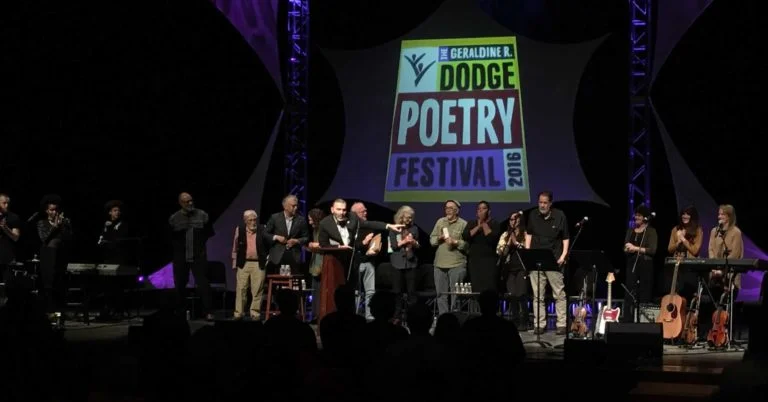 Martin Farawell, Director of the Dodge Poetry Program asks audience to give a hand to ten poets and two musical groups at Poetry like Bread: Poems of Social and Political Consciousness.