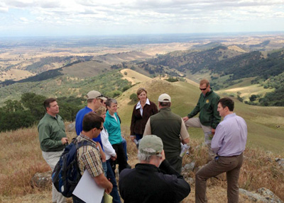 U.S. Secretary of the Interior Sally Jewell (center, in turquoise) visits Kreigor Peak with local staff and dignitaries to discuss conservation successes and take in sweeping views of land conserved through the East Contra Costa County Plan. Photo: May 2014.
