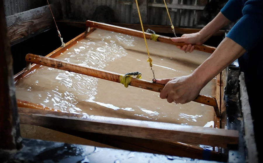 With the desired thickness in mind, Mr. Uda moves his Sugeta back and forth. He carefully watches how the fibers are formed in the screen by balancing the amount of water and the fibers flowed in. (Photo by Yoko Takahashi)