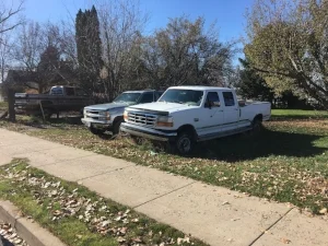 some pickuptrucks in a lot next to a house.