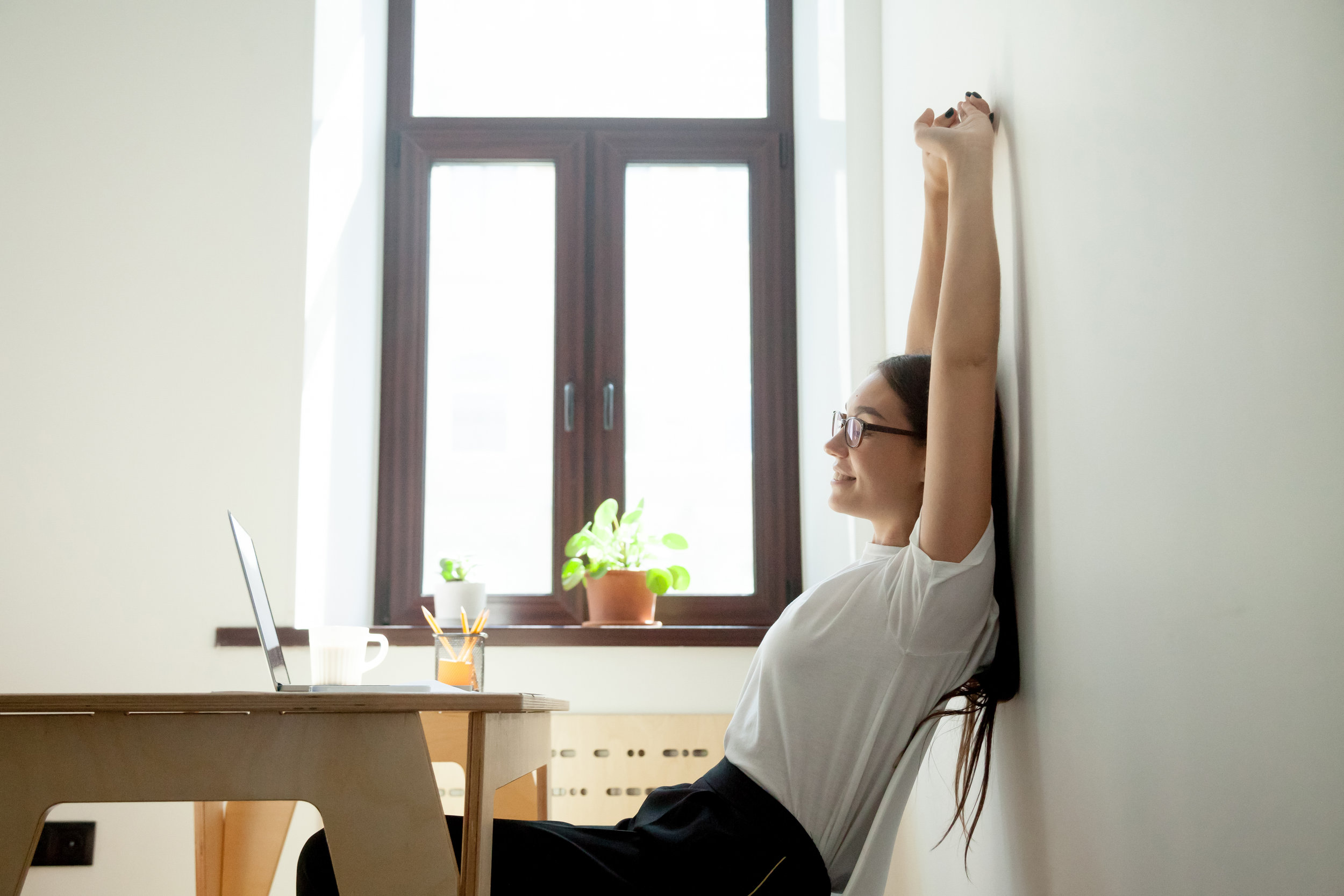 Attractive-young-businesswoman-relaxing,-stretching-at-desk-in-home-office-889206762_5349x3566.jpeg
