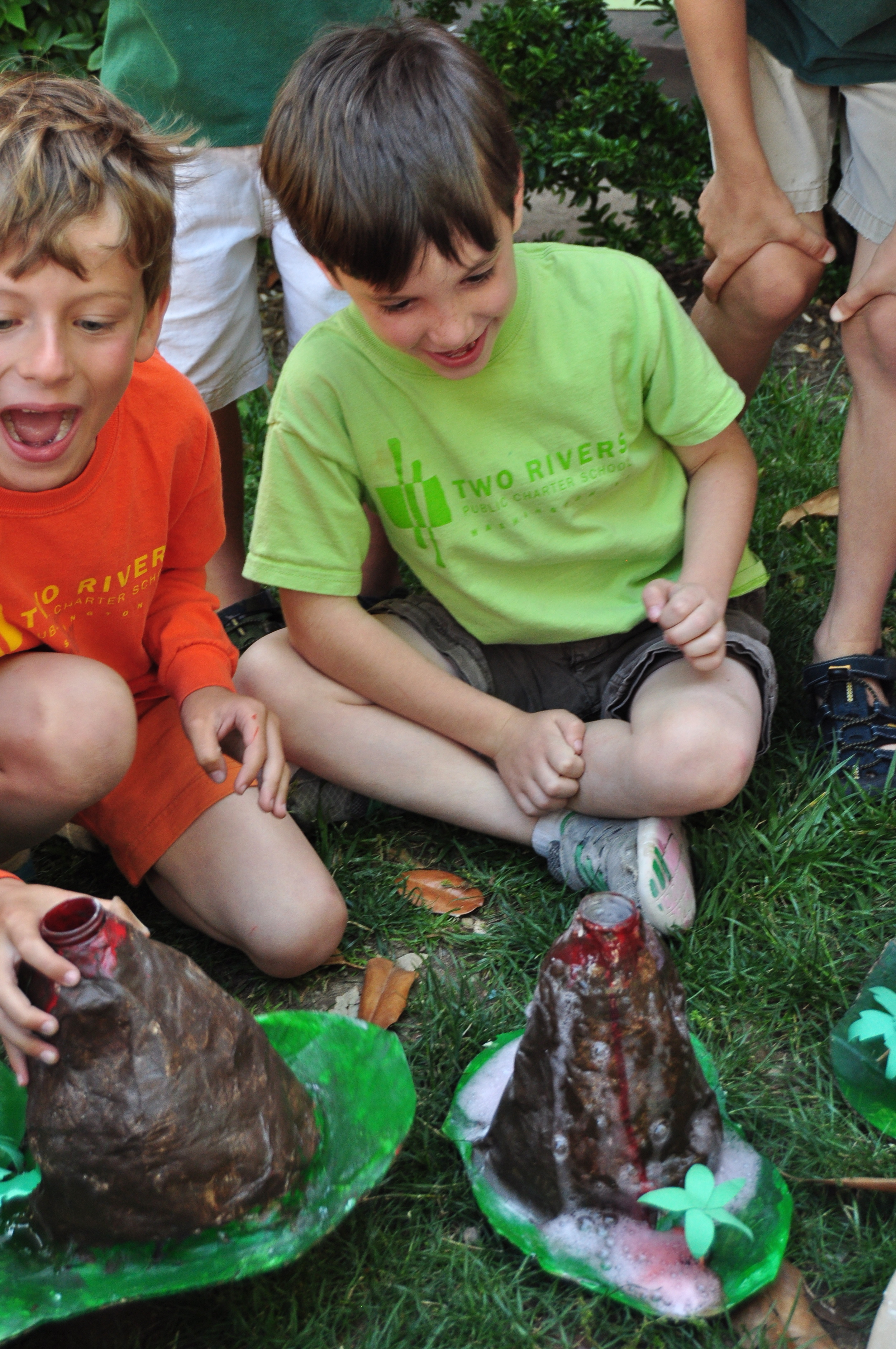  Students watching baking soda and vinegar erupt from their papier-mache volcanoes 