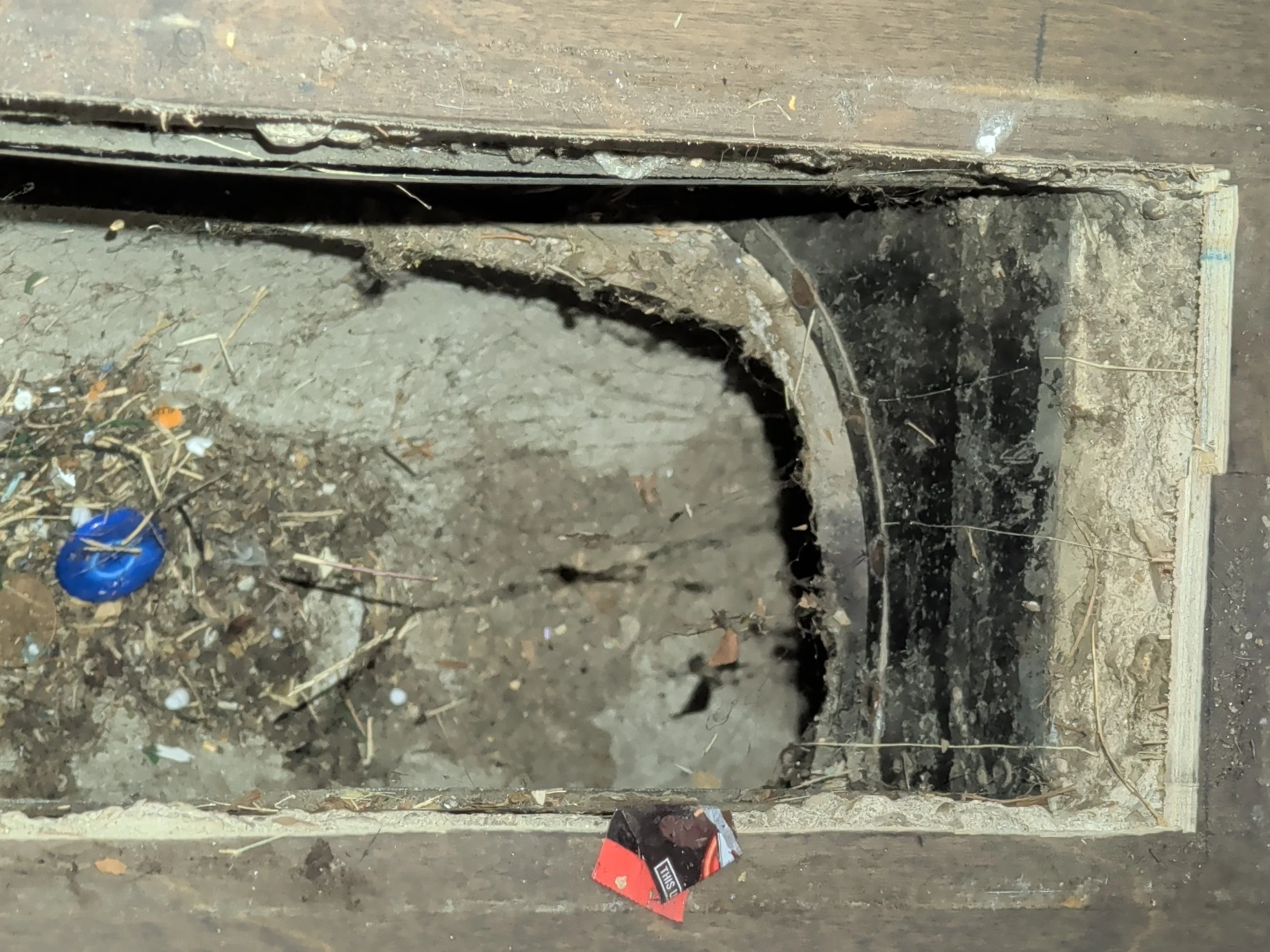 A view looking down into a sub-slab Transite HVAC duct through a floor register.