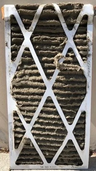 A dirty, dust-clogged residential HVAC air filter compared to a clean one.
