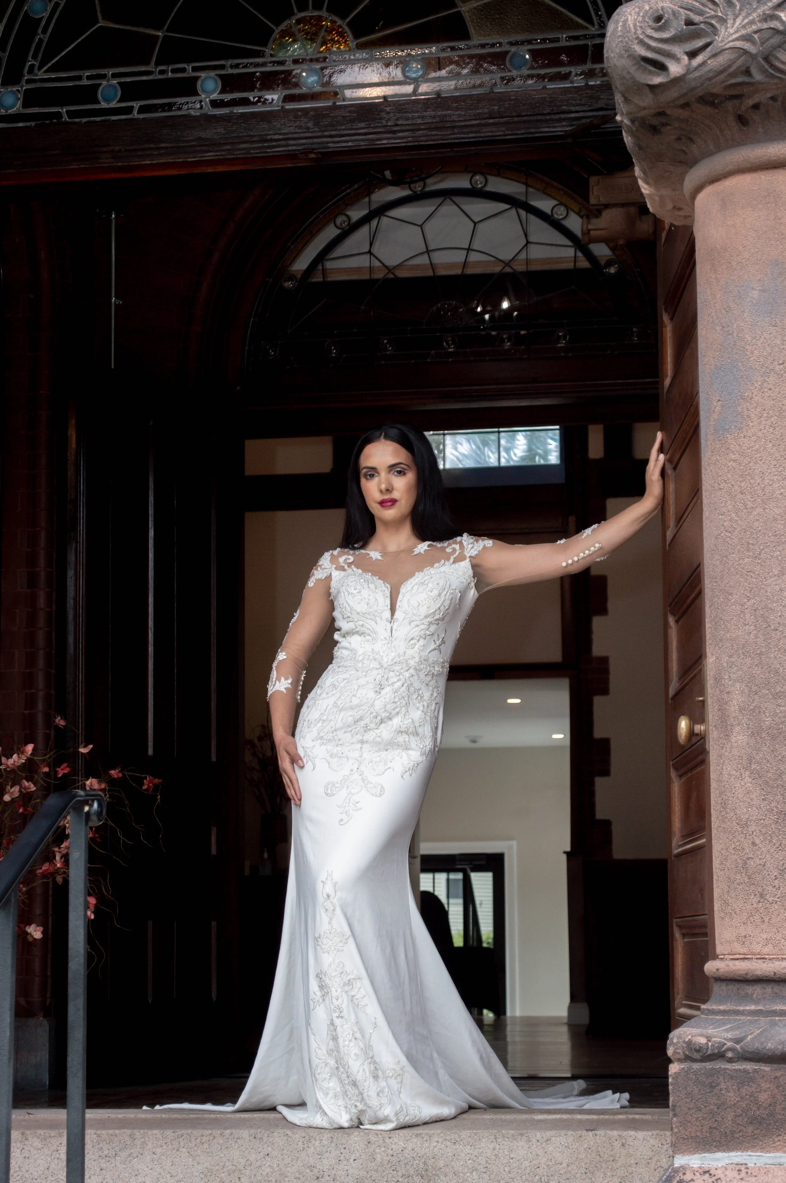 A woman in a white wedding dress standing in the doorway of a house.