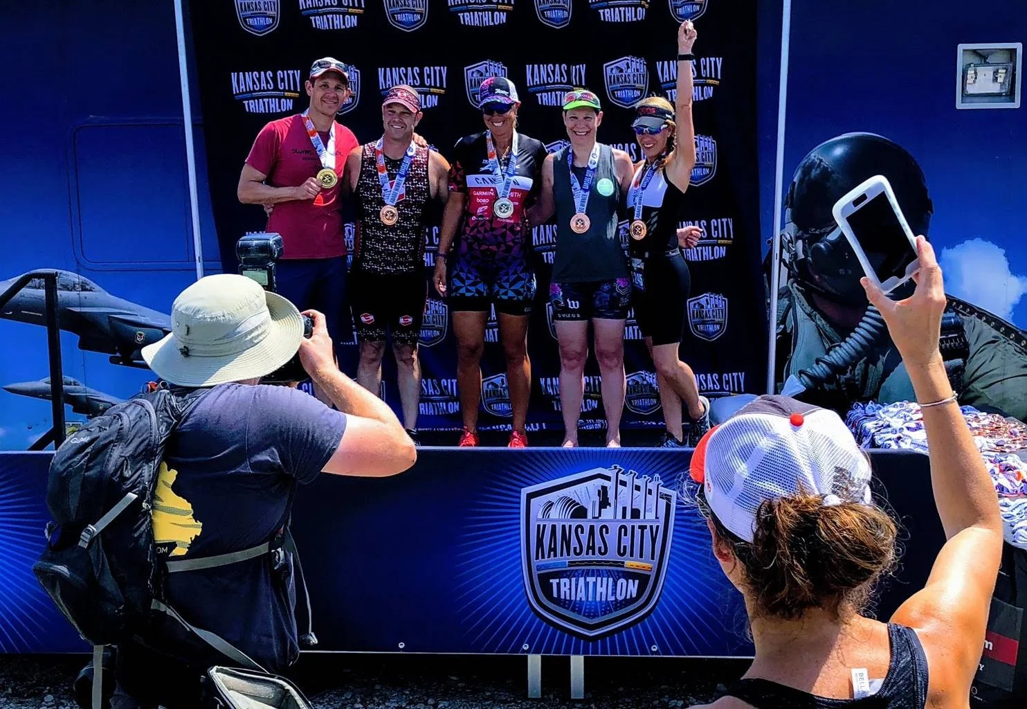 Coach Amy on the podium (far right) while her coach takes a photo with her phone.