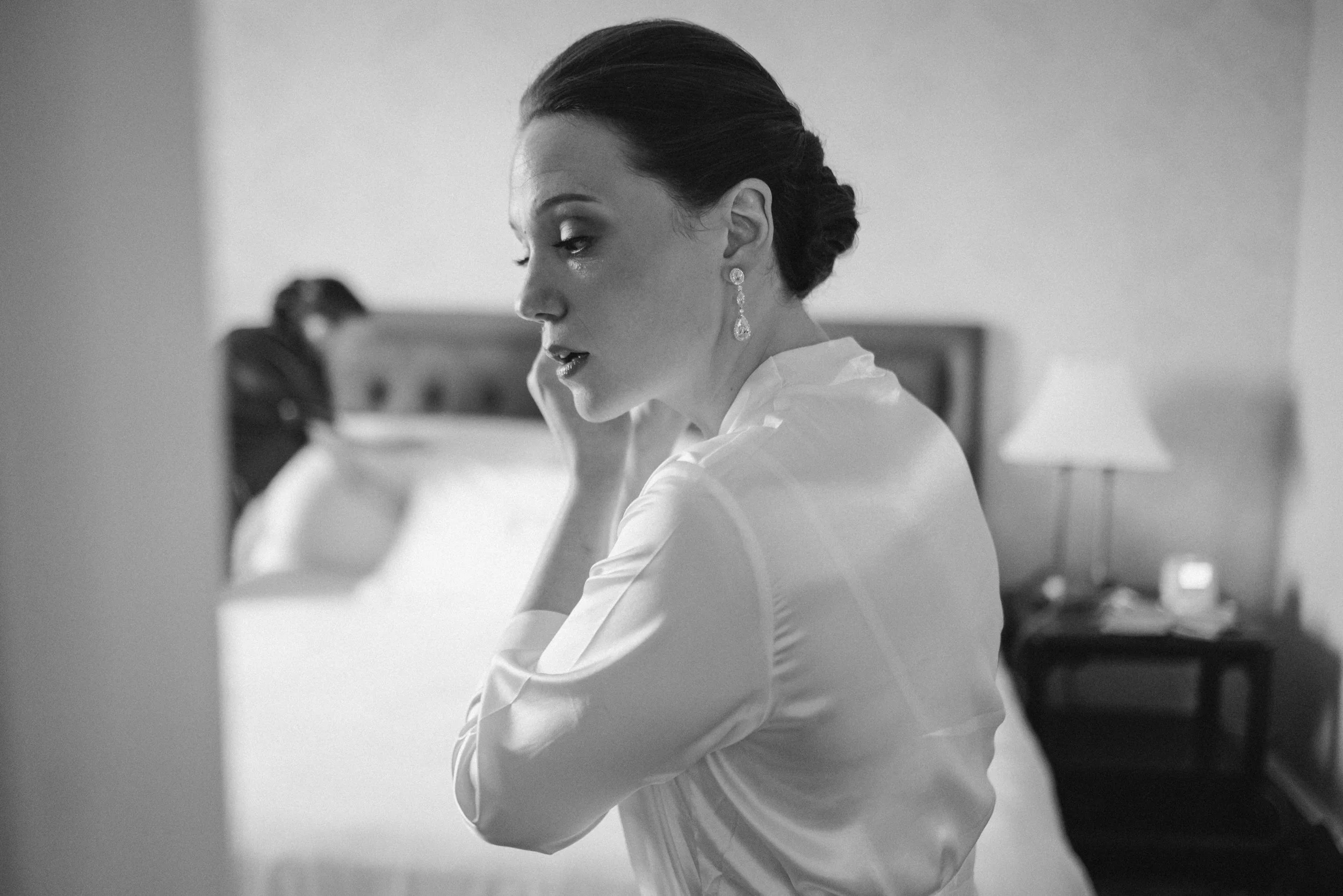 Bride putting earrings on before Peabody Essex Museum wedding ceremony.