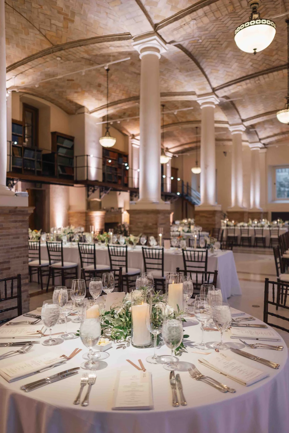 
Round table with candles and greenery centerpiece in the Guastavino Room, vaulted tile ceiling above.
