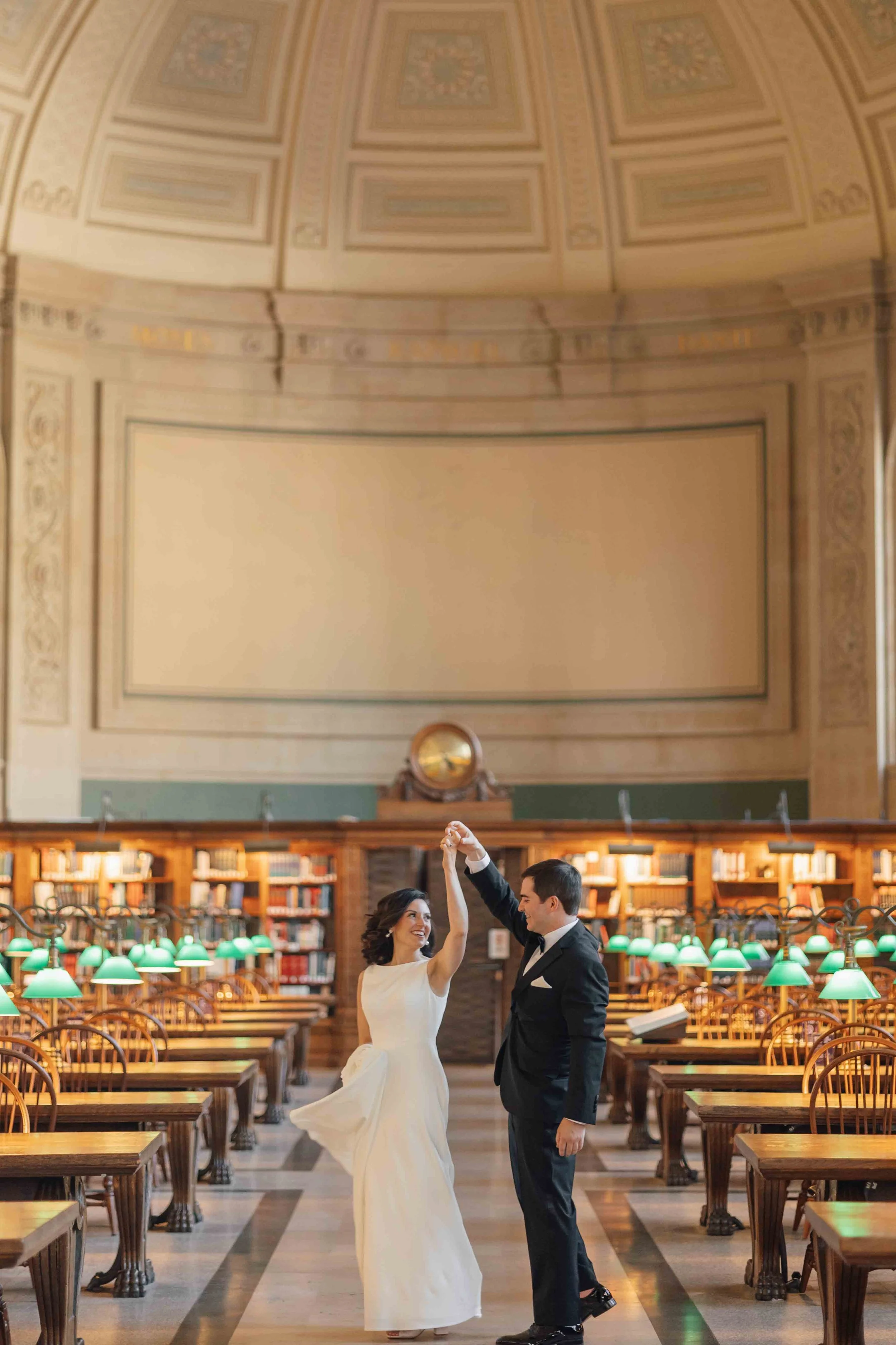 the bride and groom particing there first dance in the bates hall at the boston public library

