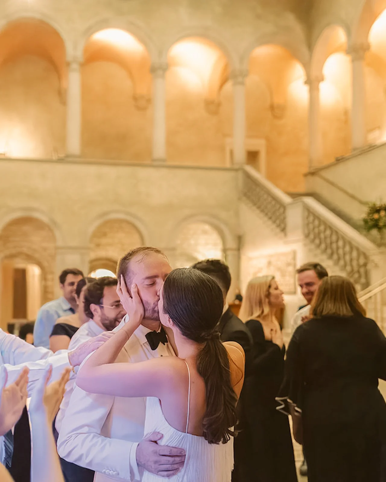 Bride and groom kiss on the dance floor at The Ringling Museum wedding in Sarasota surrounded by guests with arched colonnade and grand staircase in background