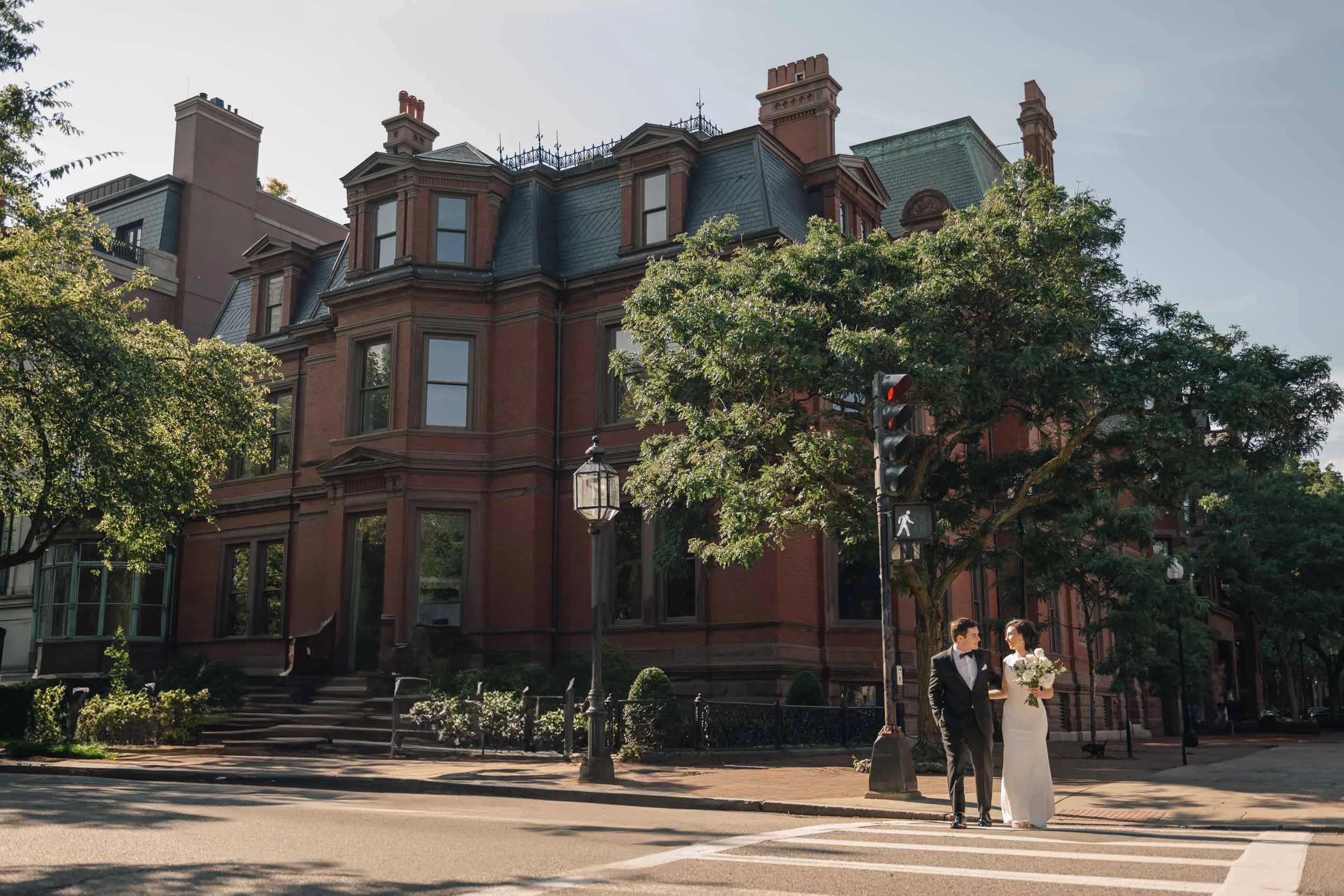 Couple crossing street outside historic brownstone near Boston Public Library.