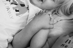 Black and white photo of two white children’s hands holding each other.