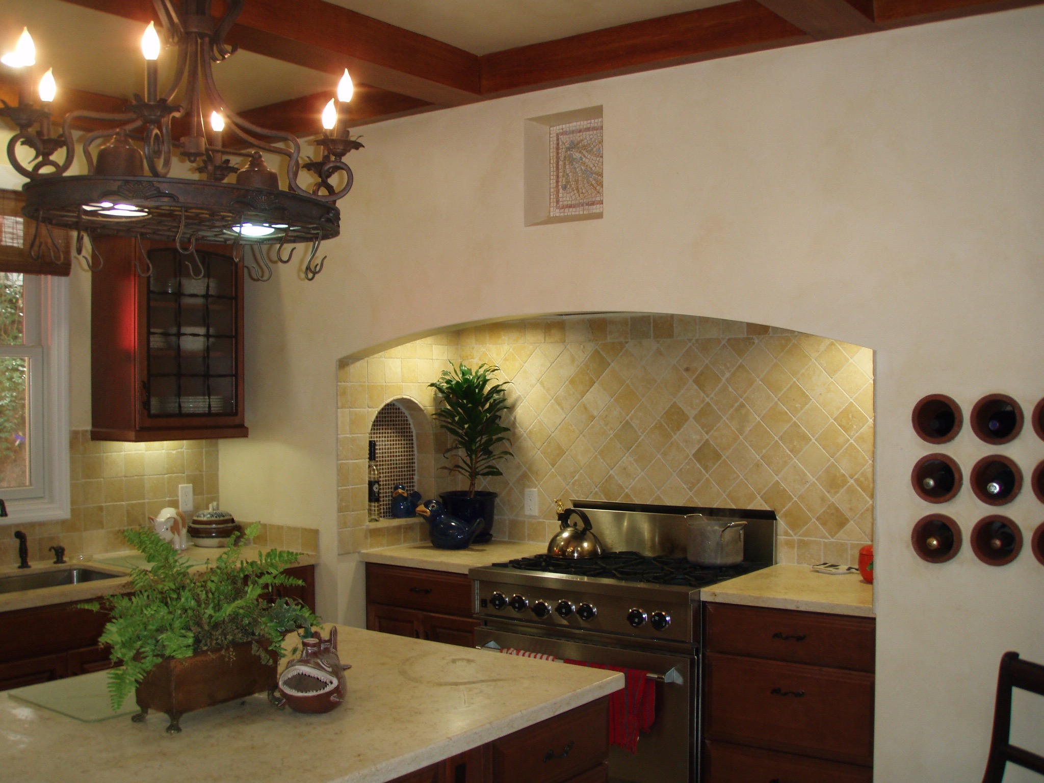 The walls have been colourwashed, the beams are painted to look like wood and the small niche above the stove has a faux mosaic panel.